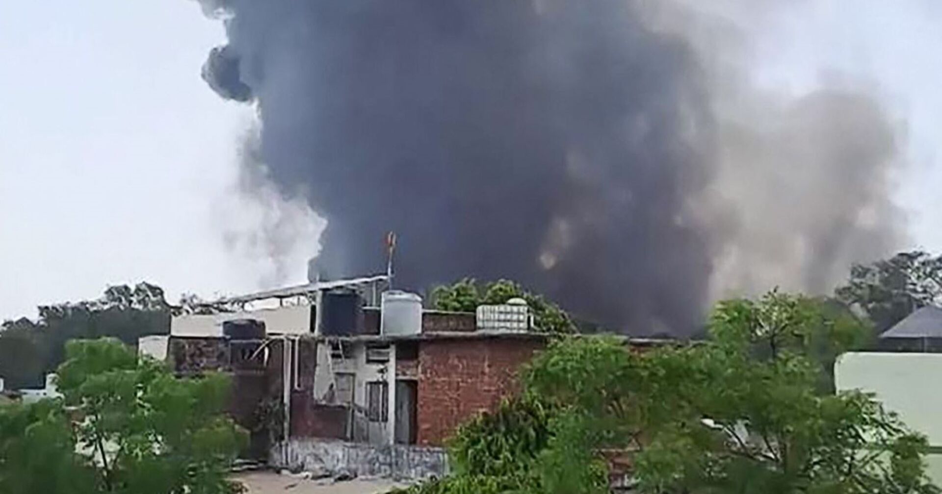 Schwarzer Rauch steigt hinter flachen Wohnhäusern in den Himmel, nachdem ein Flugzeug der Air India nahe dem Flughafen von Ahmedabad abgestürzt ist.