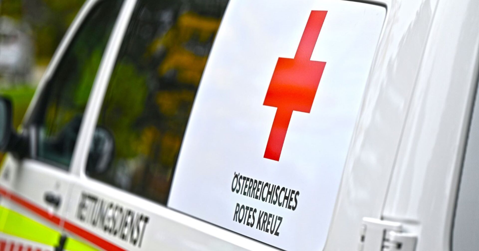 Ein Rettungsauto des Österreichischen Roten Kreuzes mit rotem Kreuz-Symbol und der Aufschrift „ÖSTERREICHISCHES ROTES KREUZ“ an der Fahrzeugseite.