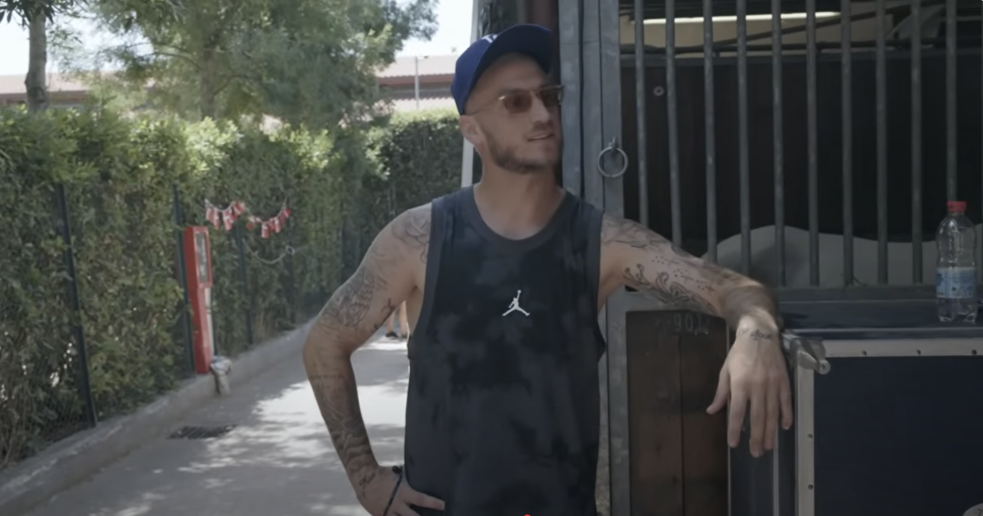 Marko Arnautović mit Sonnenbrille und blauer Kappe in einem Pferdestall, leicht lächelnd, im Hintergrund Holzstallwände und Grün.