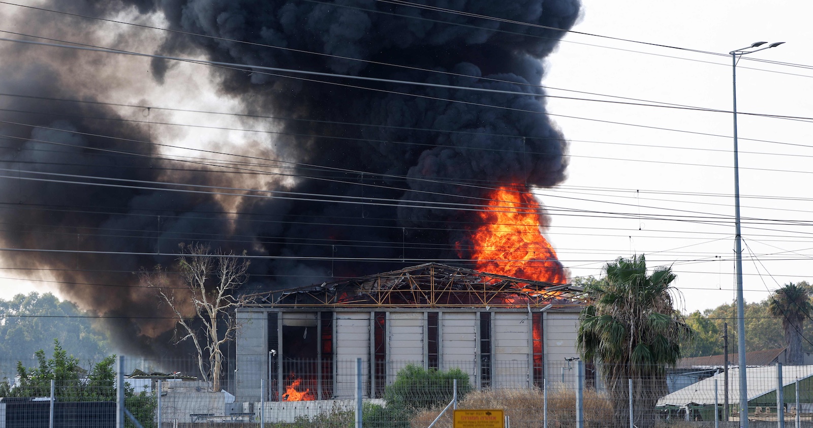 Dunkle Rauchwolken und lodernde Flammen steigen aus einem brennenden Gebäude auf, das offenbar nach einem Angriff schwer beschädigt wurde.