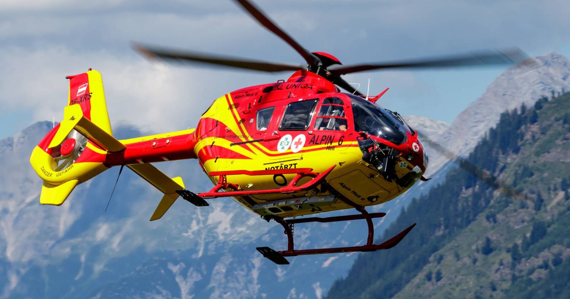 Nahaufnahme eines Rettungshubschraubers vor einer imposanten Bergkulisse