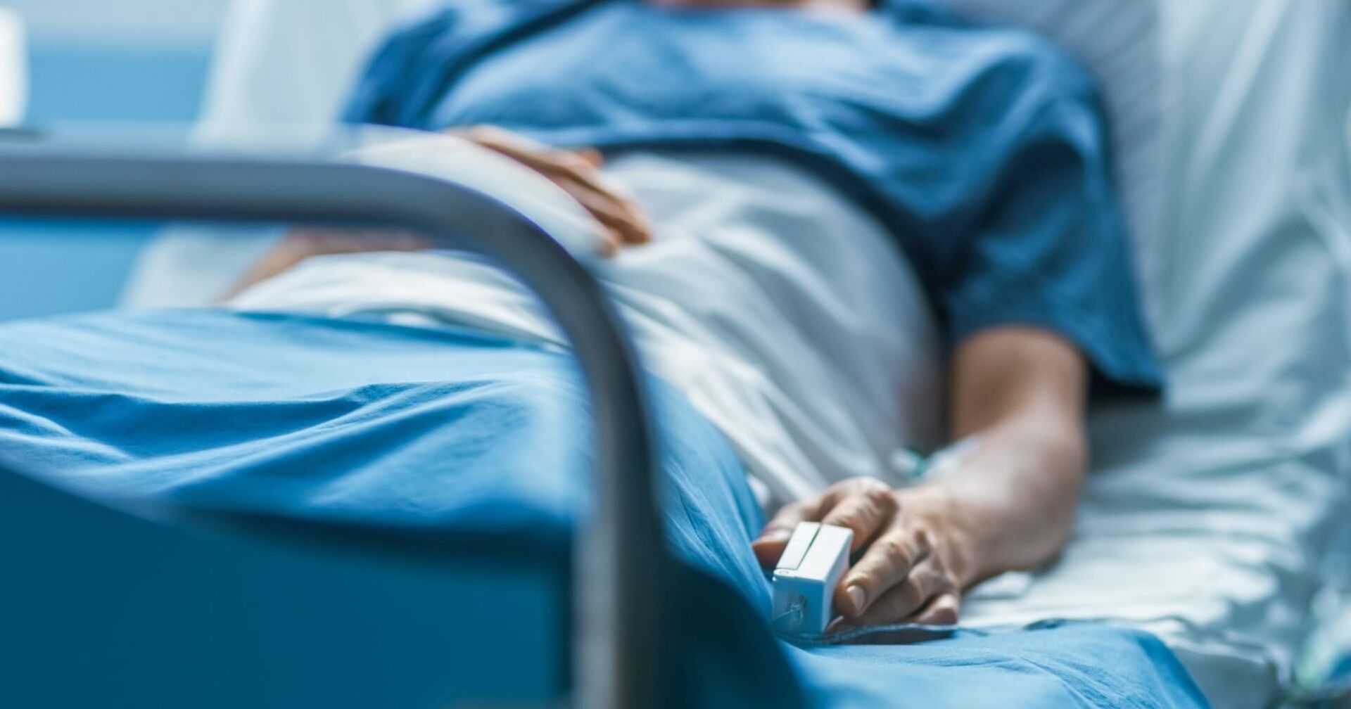 Im Krankenhaus schläft kranker männlicher Patient auf dem Bett. Ein Herzfrequenzmesser ist an seinem Finger.