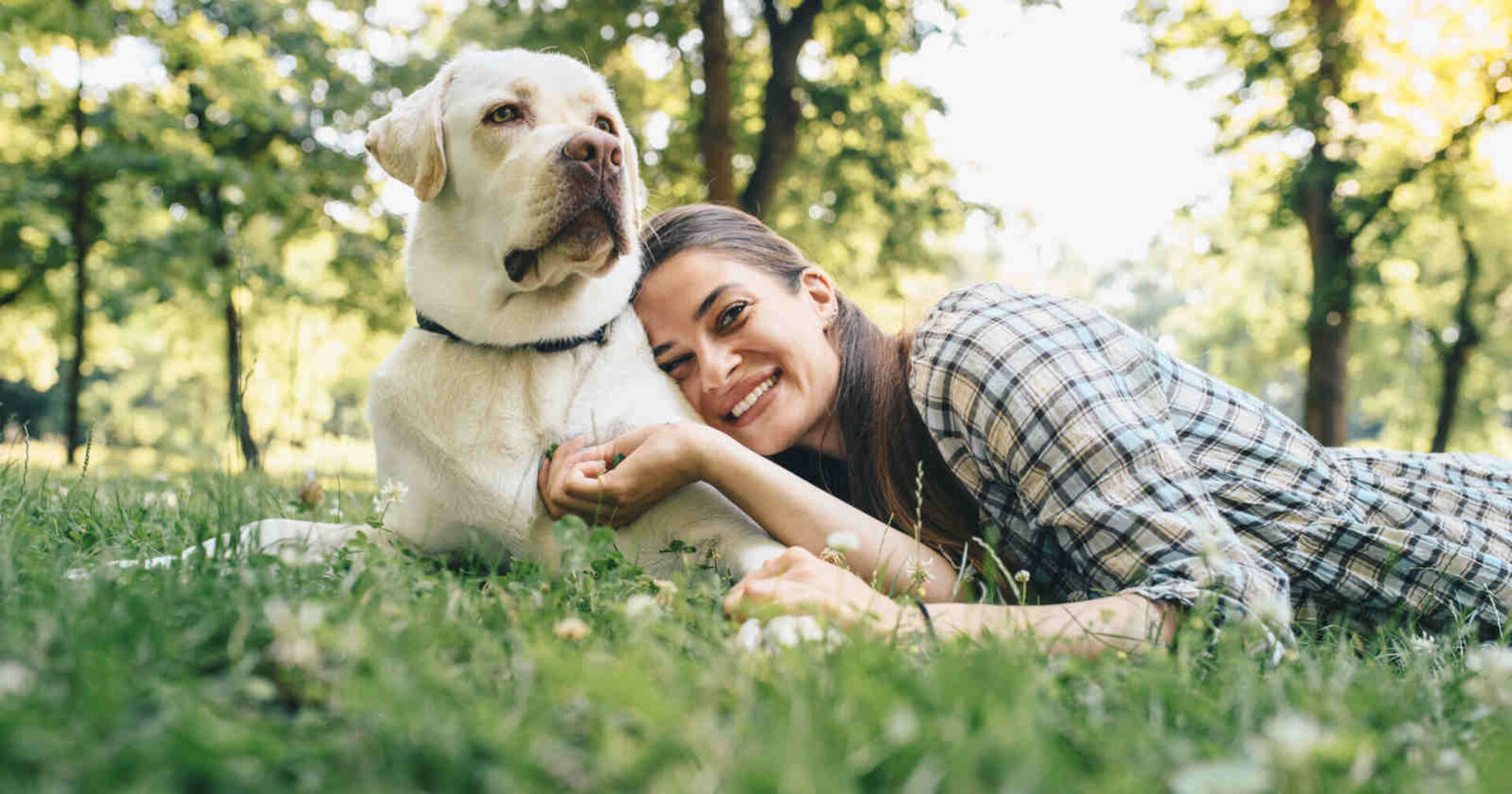 Frau liegt neben einem Hund im Gras