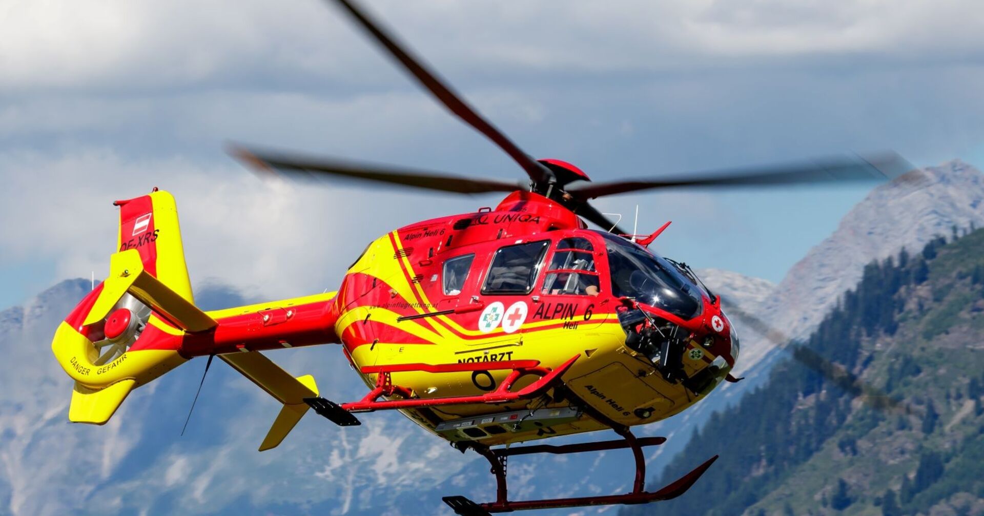 rot-gelber Notarzt-Helikopter in den Bergen