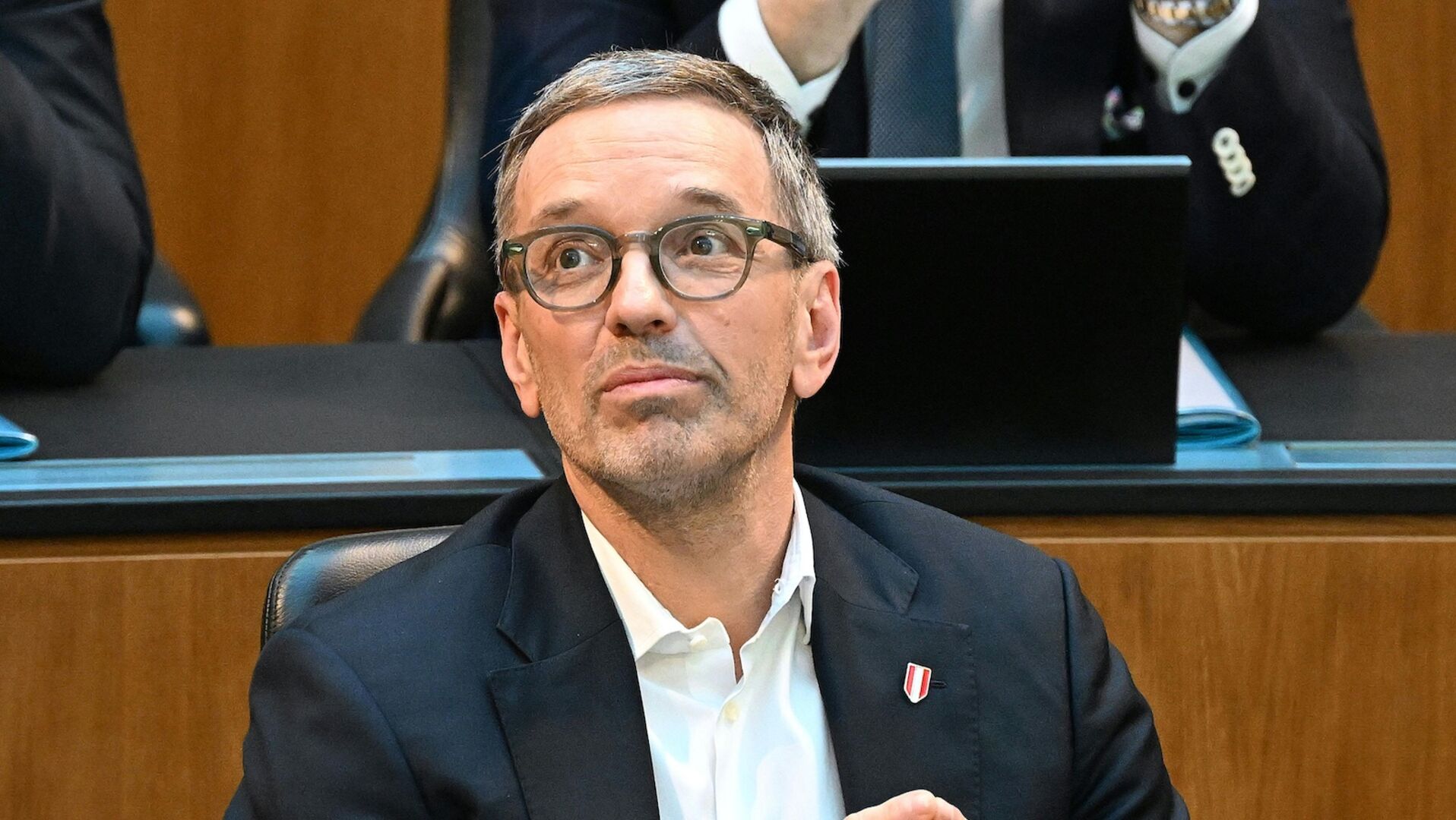 Herbert Kickl im Anzug mit Brille sitzt nachdenklich im Nationalrat.
