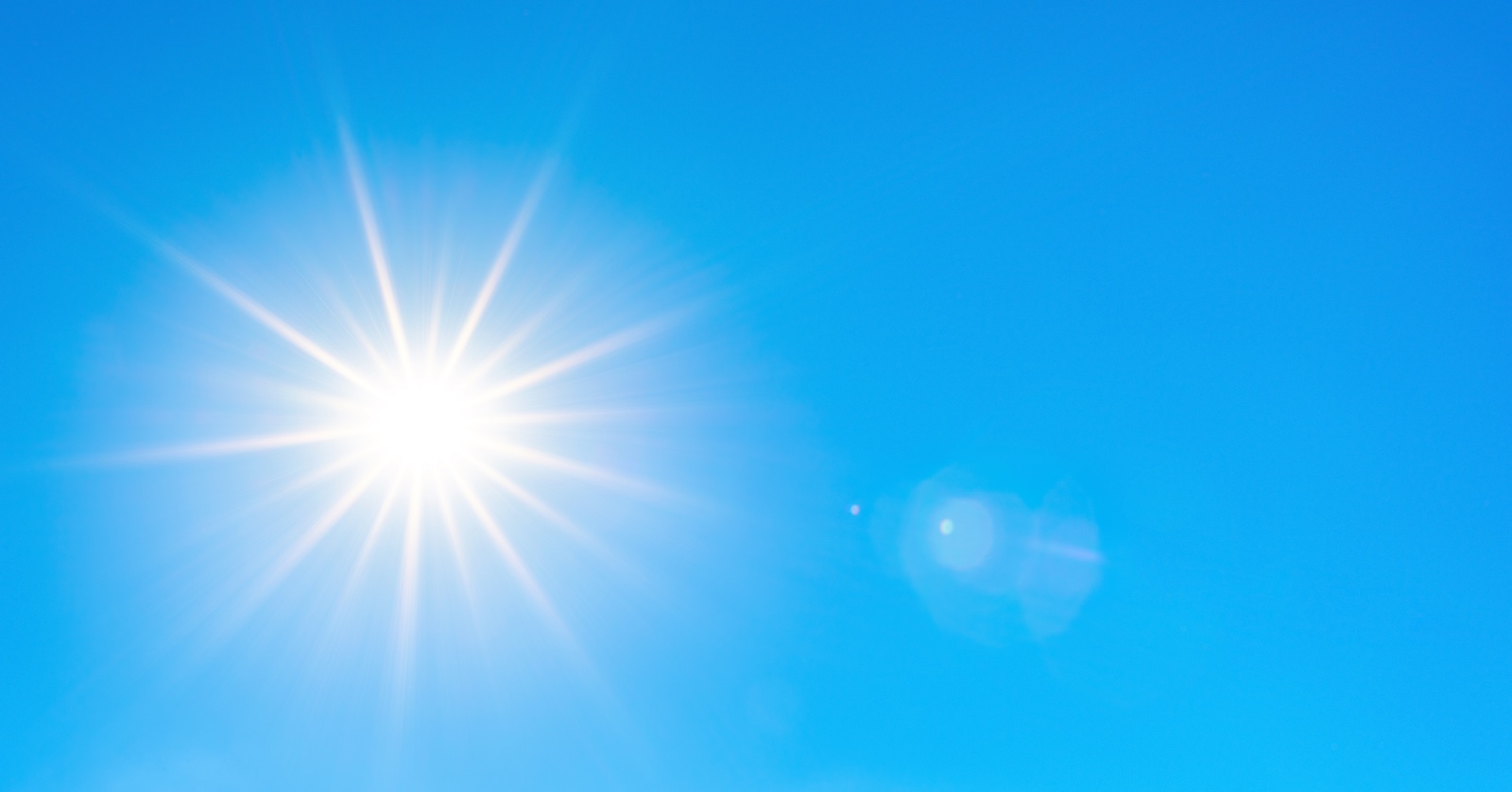 Die Sonne scheint hell am blauen Himmel, typische Darstellung für eine sommerliche Hitzewelle mit Temperaturen über 30 Grad in Österreich.
