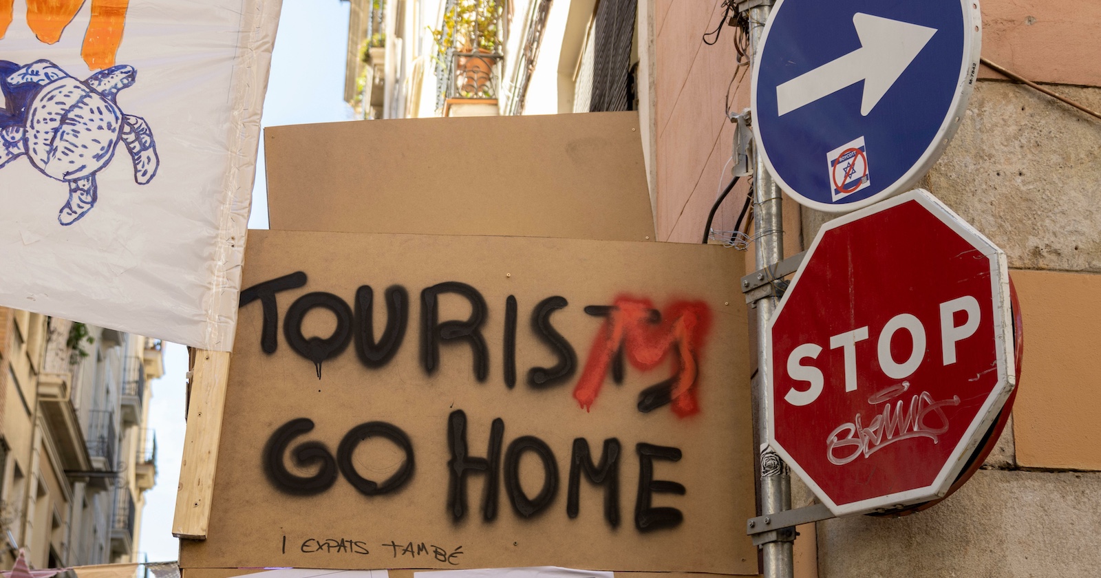Protestplakat mit der Aufschrift „Tourists go home“ und Stoppschild in Barcelonas Altstadt