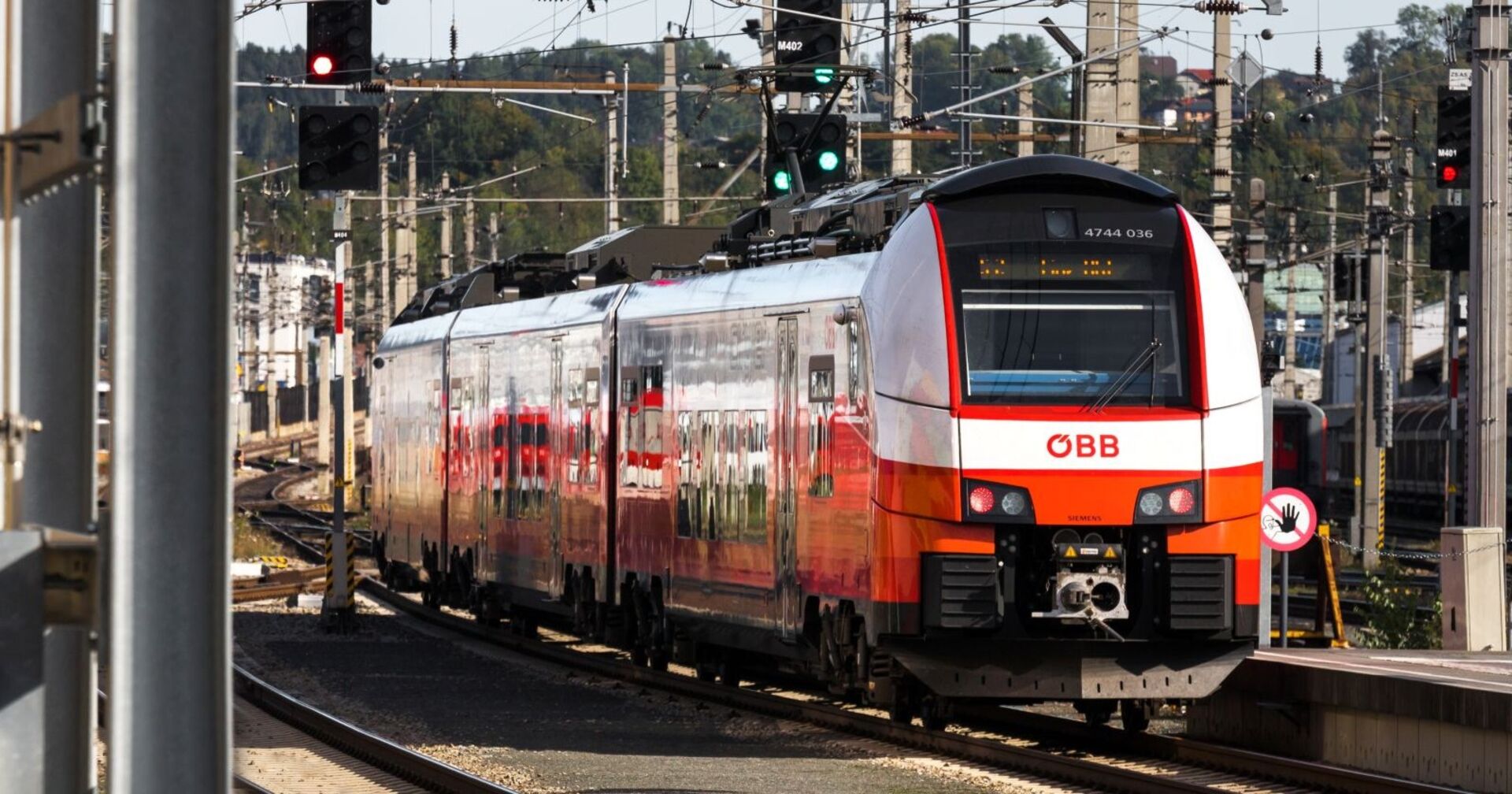 ÖBB-Zug auf der Stammstrecke in Wien, im Bereich eines Bahnhofs mit Signalanlagen und Gleisen im Vordergrund.