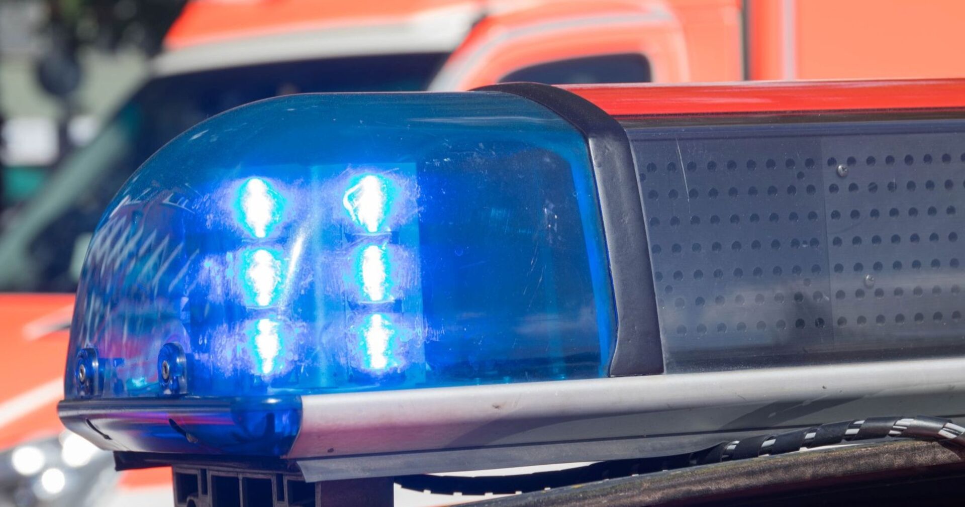 Blaulicht eines Polizeifahrzeugs im Einsatz, unscharf im Hintergrund ein Einsatzfahrzeug.