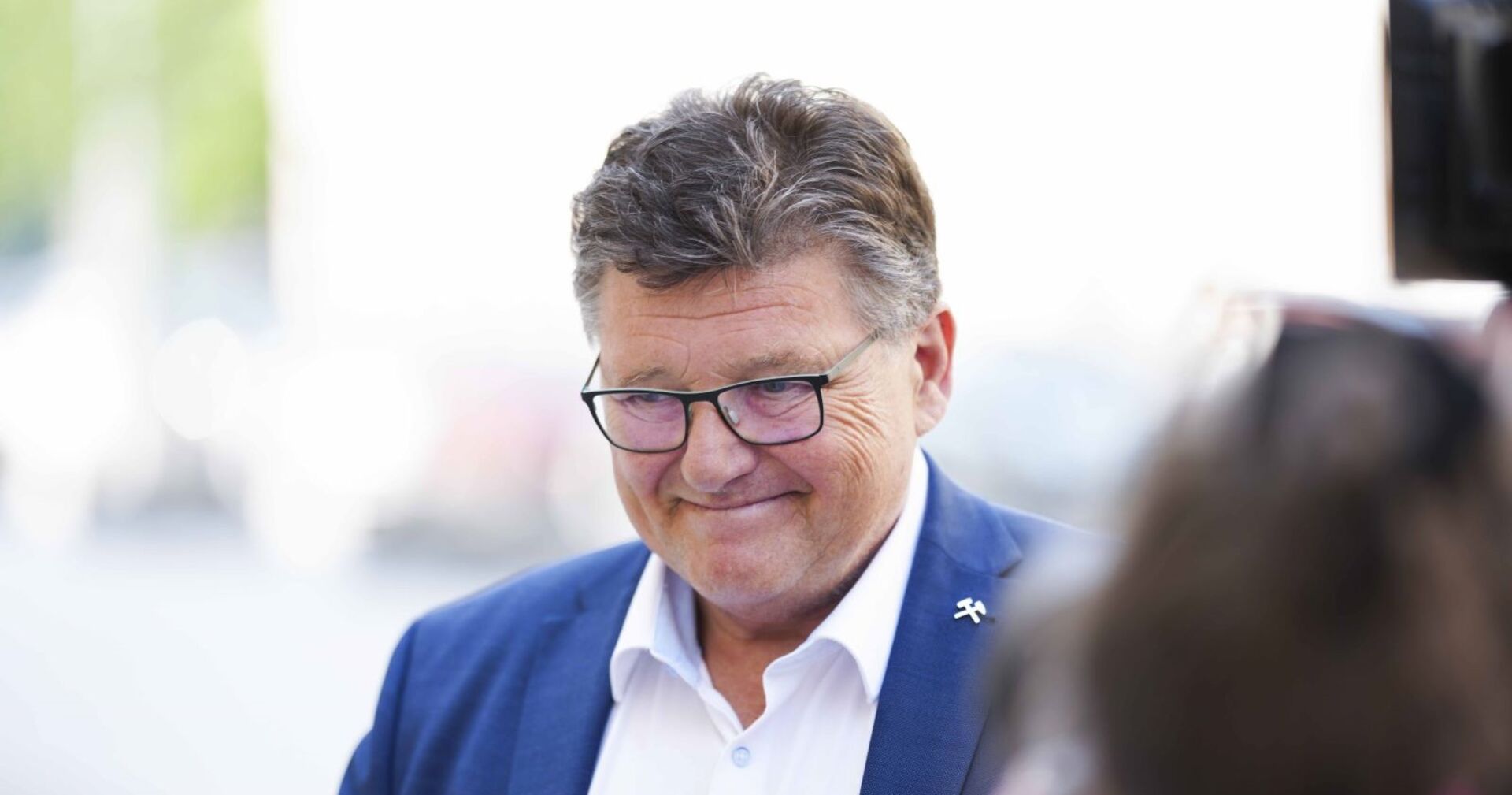 Rainer Wimmer lächelt in einem blauen Sakko mit weißem Hemd und Brille, aufgenommen im Freien bei einem Pressetermin.