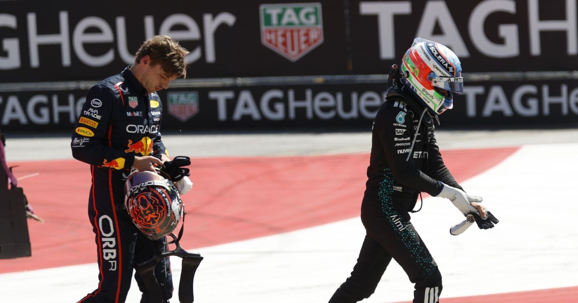 Red-Bull-Fahrer Verstappen hält seinen Helm und blickt frustriert zu Boden, während Mercedes-Pilot Antonelli mit Helm und Handschuhen davonläuft – Szene nach einem Unfall auf einer Formel-1-Strecke.