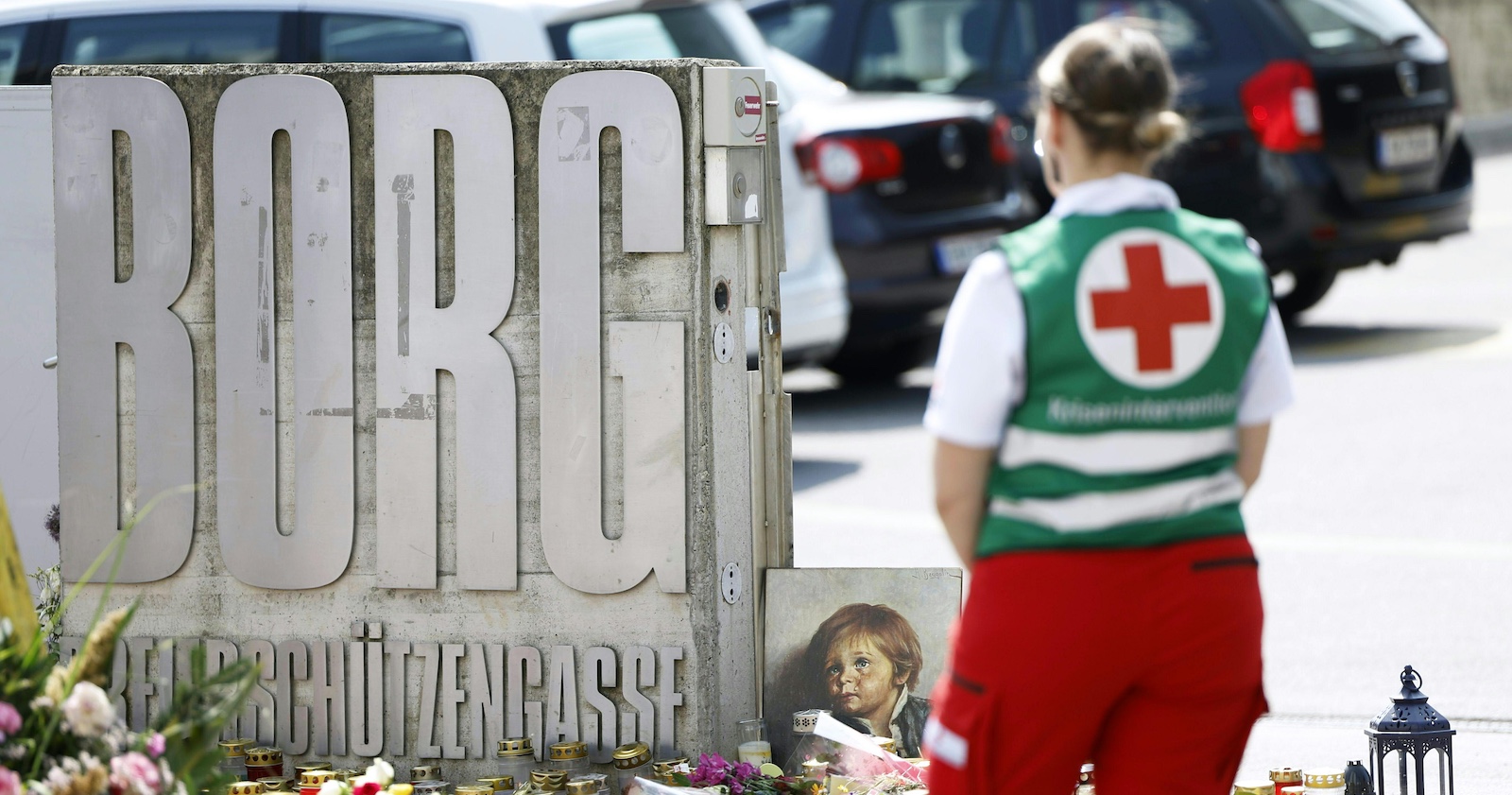 Eine Mitarbeiterin des Roten Kreuzes steht vor dem Eingang des BORG Monsbergergasse in Graz, wo Blumen und Kerzen nach dem Amoklauf niedergelegt wurden. Die Tat erschütterte ganz Österreich.