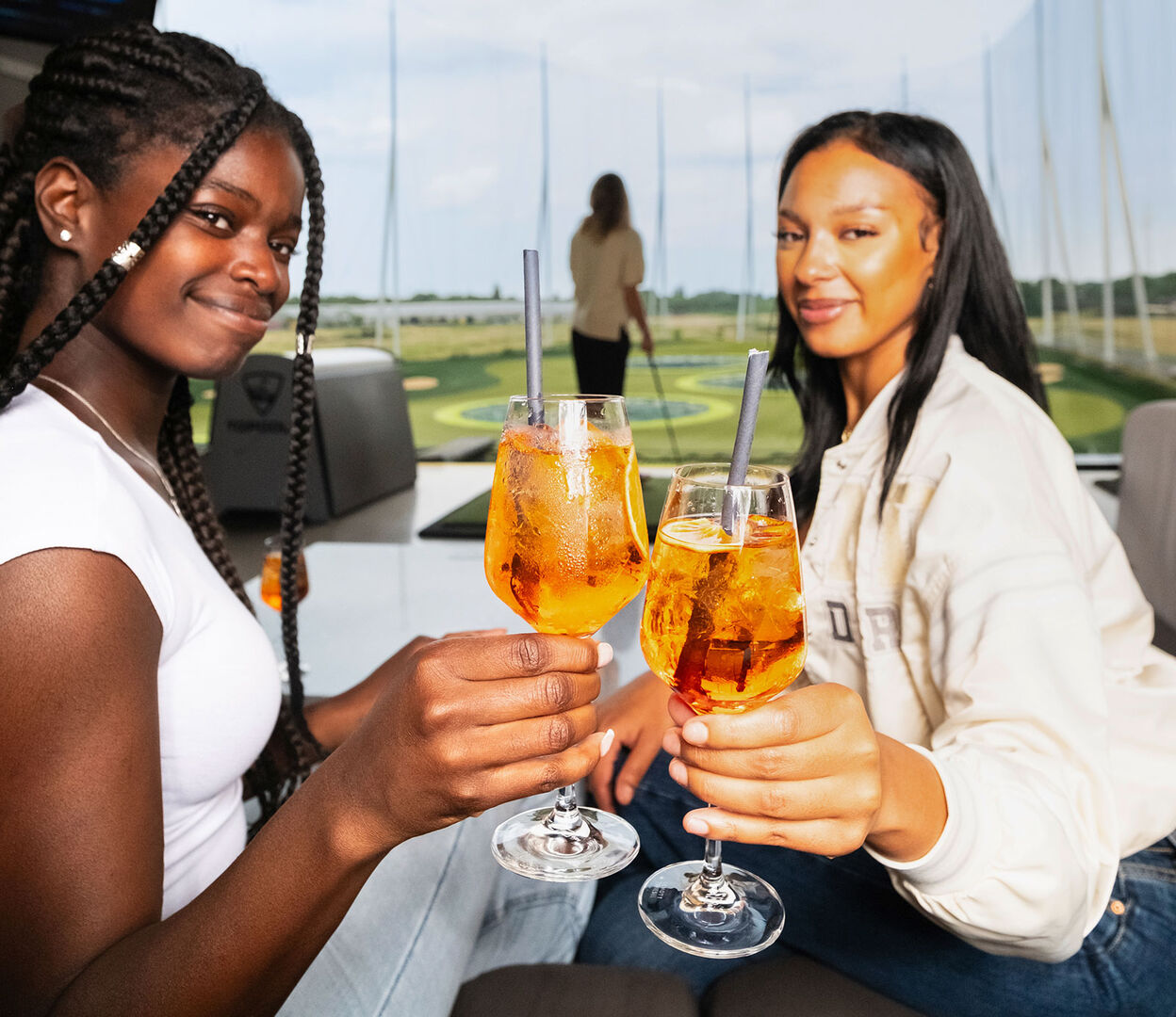 Zwei junge Frauen prosten sich mit Cocktails zu | Credit: Topgolf Wien