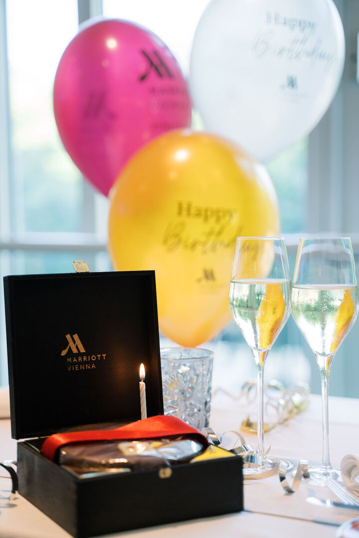 Schwarze Schachtel mit Torte und zwei Sektgläsern und Ballons | Credit: Vienna Marriott Hotel