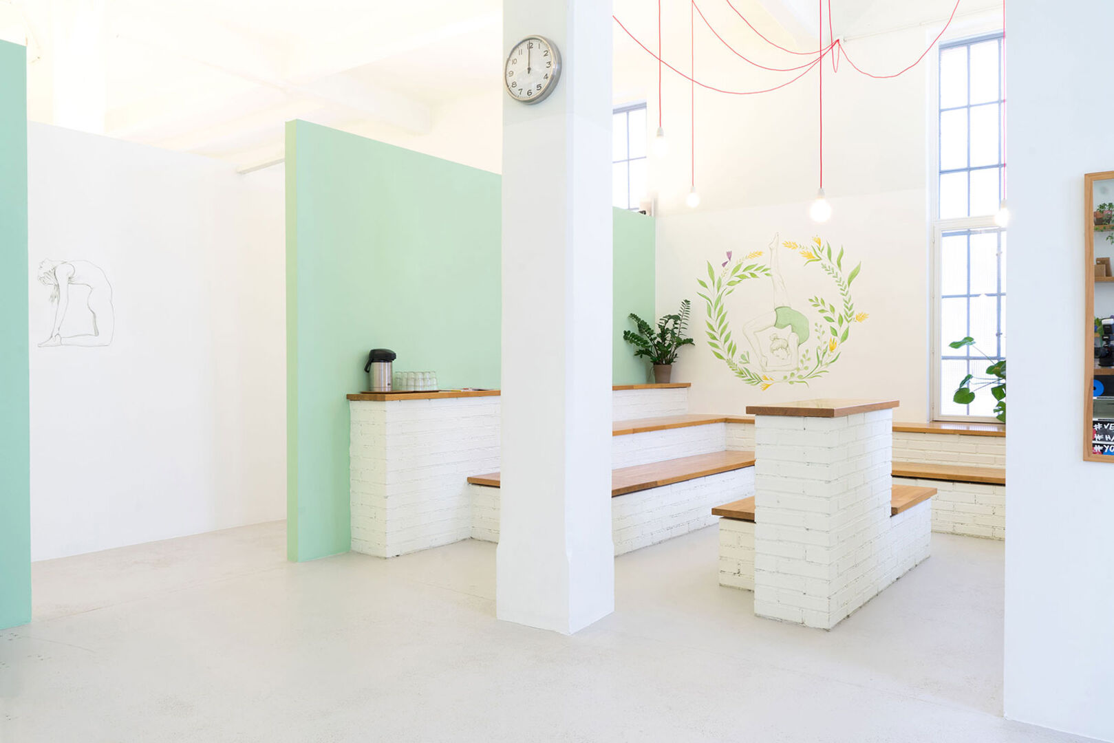 Freundlich gestalteter Empfangsbereich in hellen Farben | Hell erleuchtetes Yoga-Studio | Credit: Yoga Loft Wien/Moritz Zangl