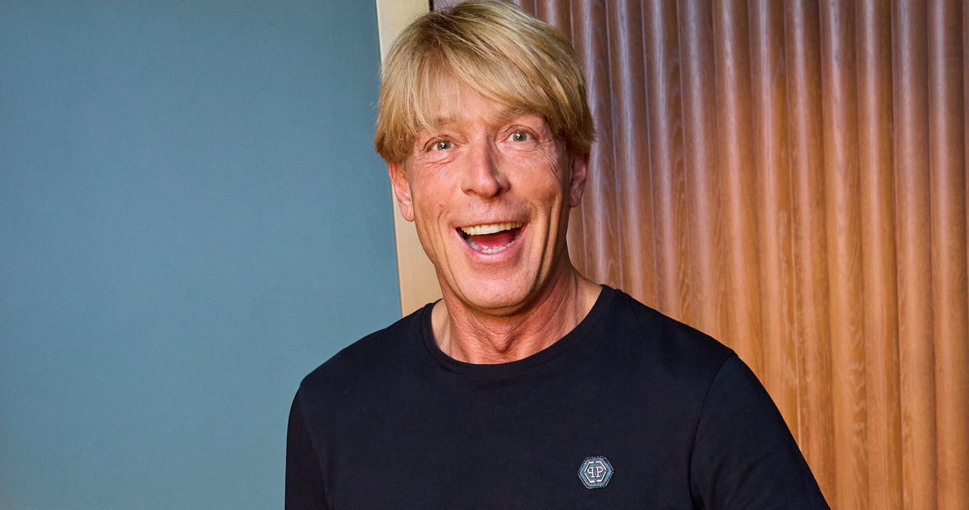 Dominic Heinzl im schwarzen Shirt grinst breit in die Kamera