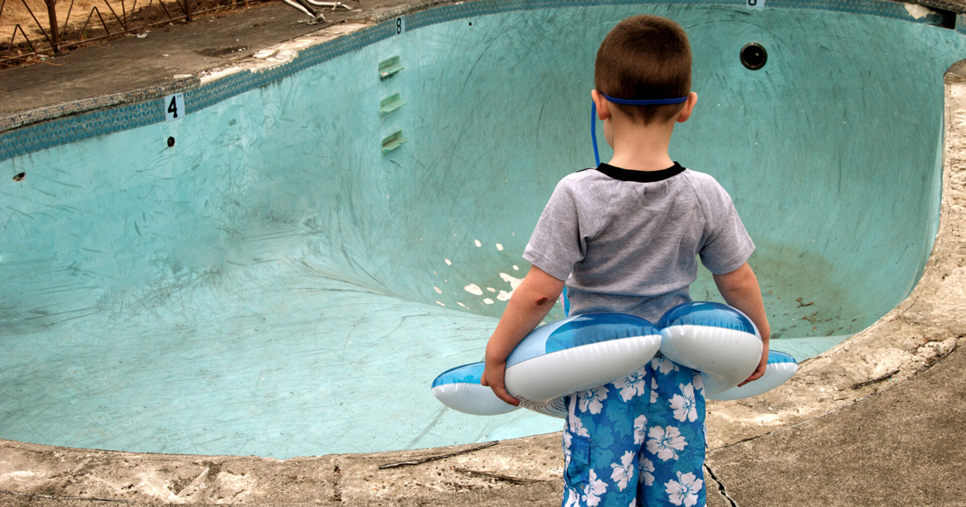Kleiner junge vor kaputtem Pool | Credit: iStock.com/RickLordPhotography