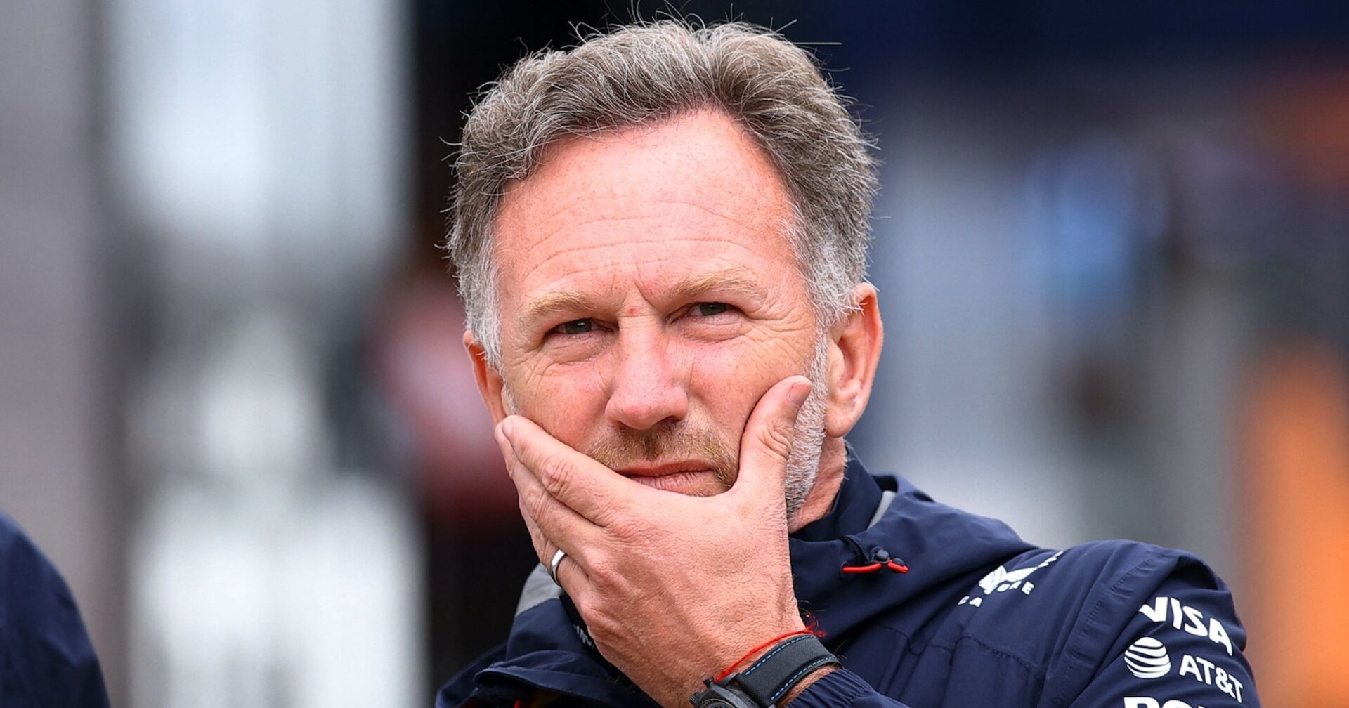 Christian Horner mit nachdenklichem Gesichtsausdruck, die Hand am Kinn, in Red-Bull-Teamkleidung.