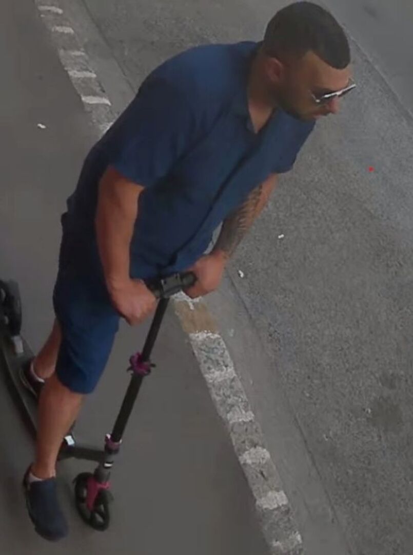 Fahndungsfoto: Mann am Roller, im blauen Hemd mit Tattoo am linken Arm und kurzen Haaren und Drei-Tage-Bart