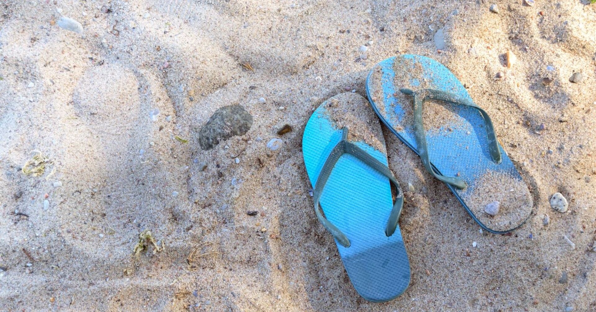 blaue Flip Flops im Sand