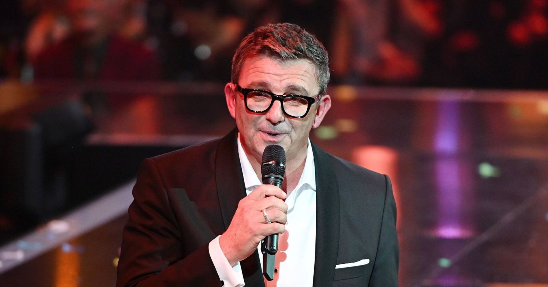 Hans Sigl mit Mikrophon und Brille