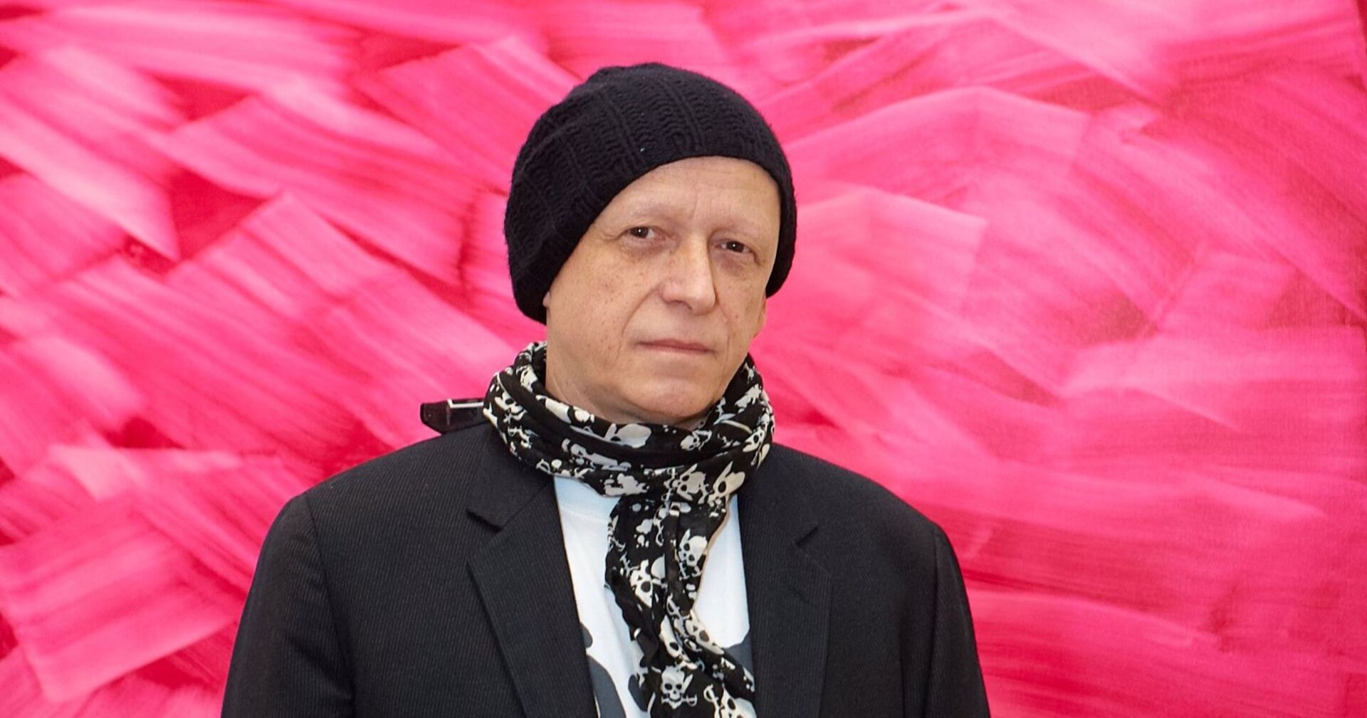 Herbert Brandl mit schwarzer Haube und pinkem Hintergrund