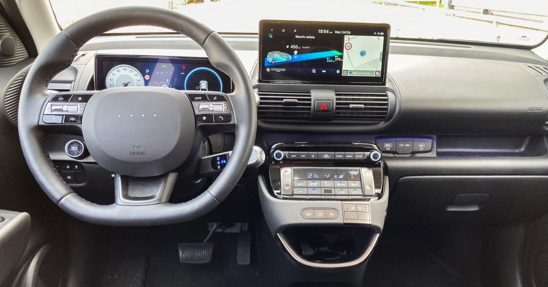 Das Cockpit des Hyundai Inster: Lenkrad und Co. sind grau gefärbt, in der Mitte sieht man das rechteckige Display des Navigationsgerätes.