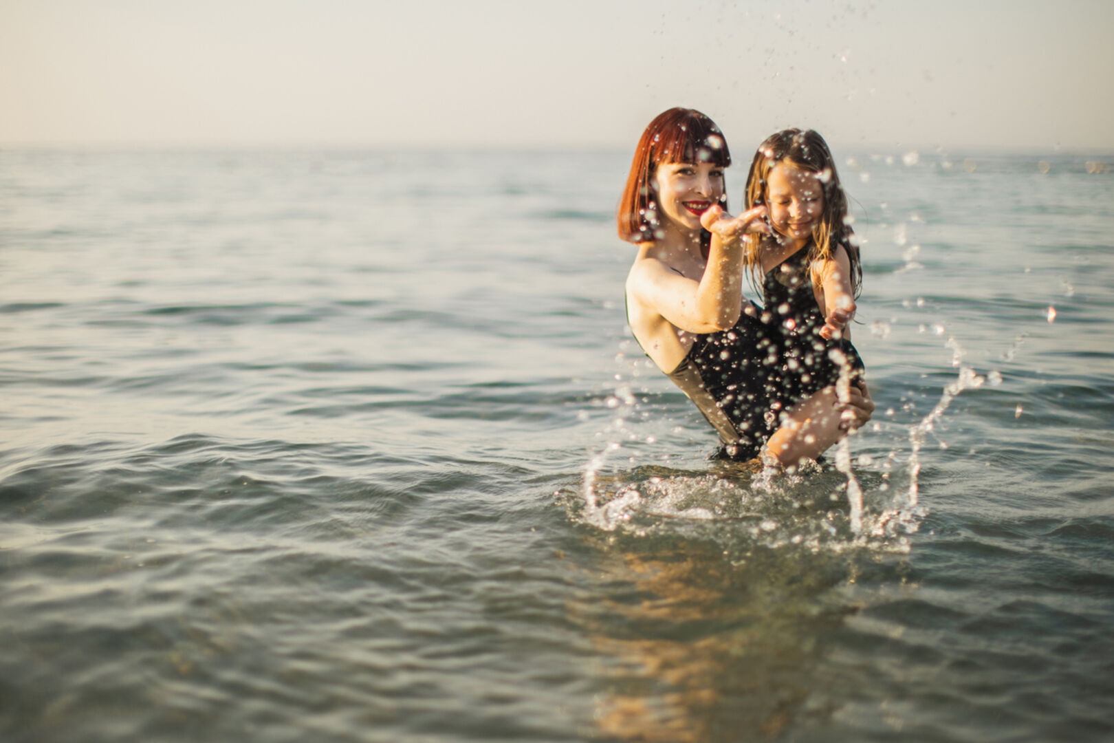 Eine rothaarige Mutter und ihre Tochter baden im Meer