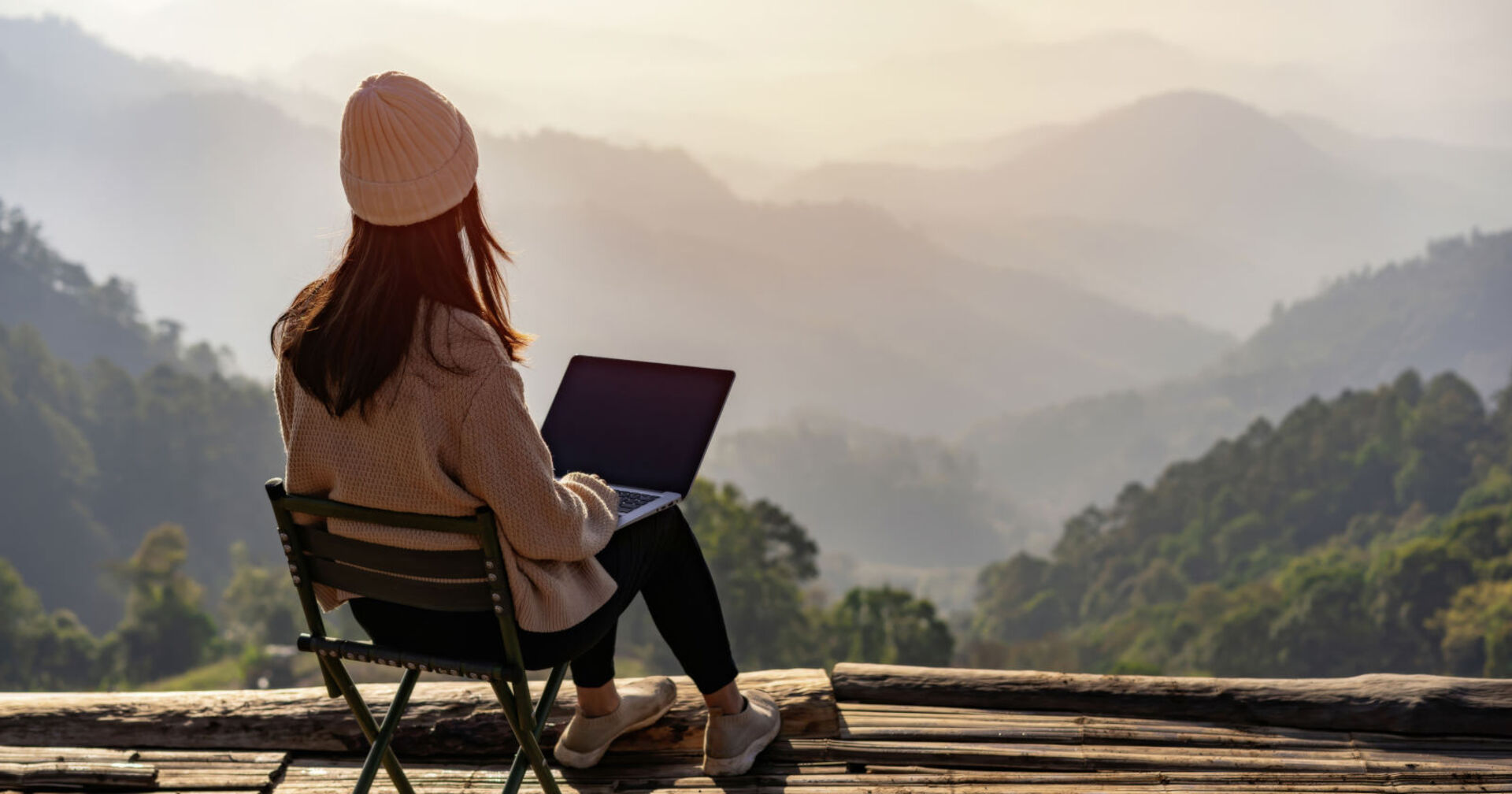 Frau arbeitet auf ihrem Laptop vor einer Bergkulisse