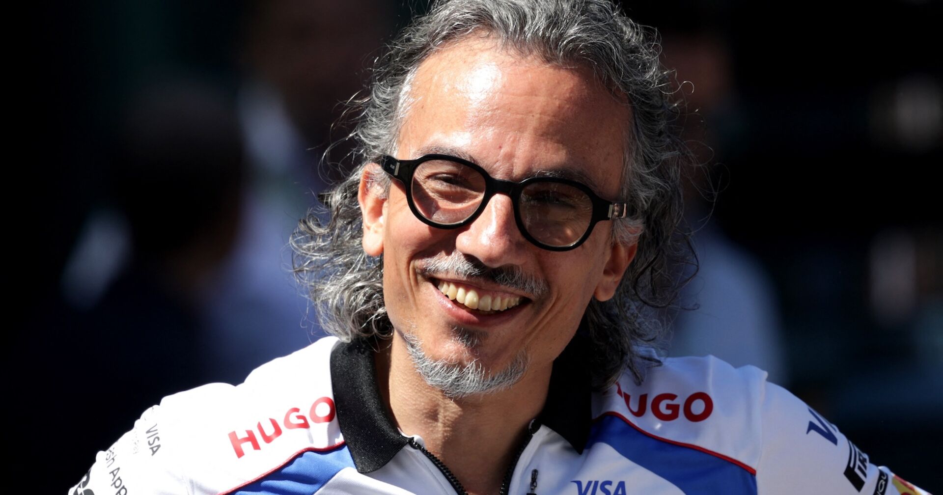 Porträt von Laurent Mekies mit Brille und leicht grauem Haar, lächelnd im Racing-Bulls-Teamoutfit.