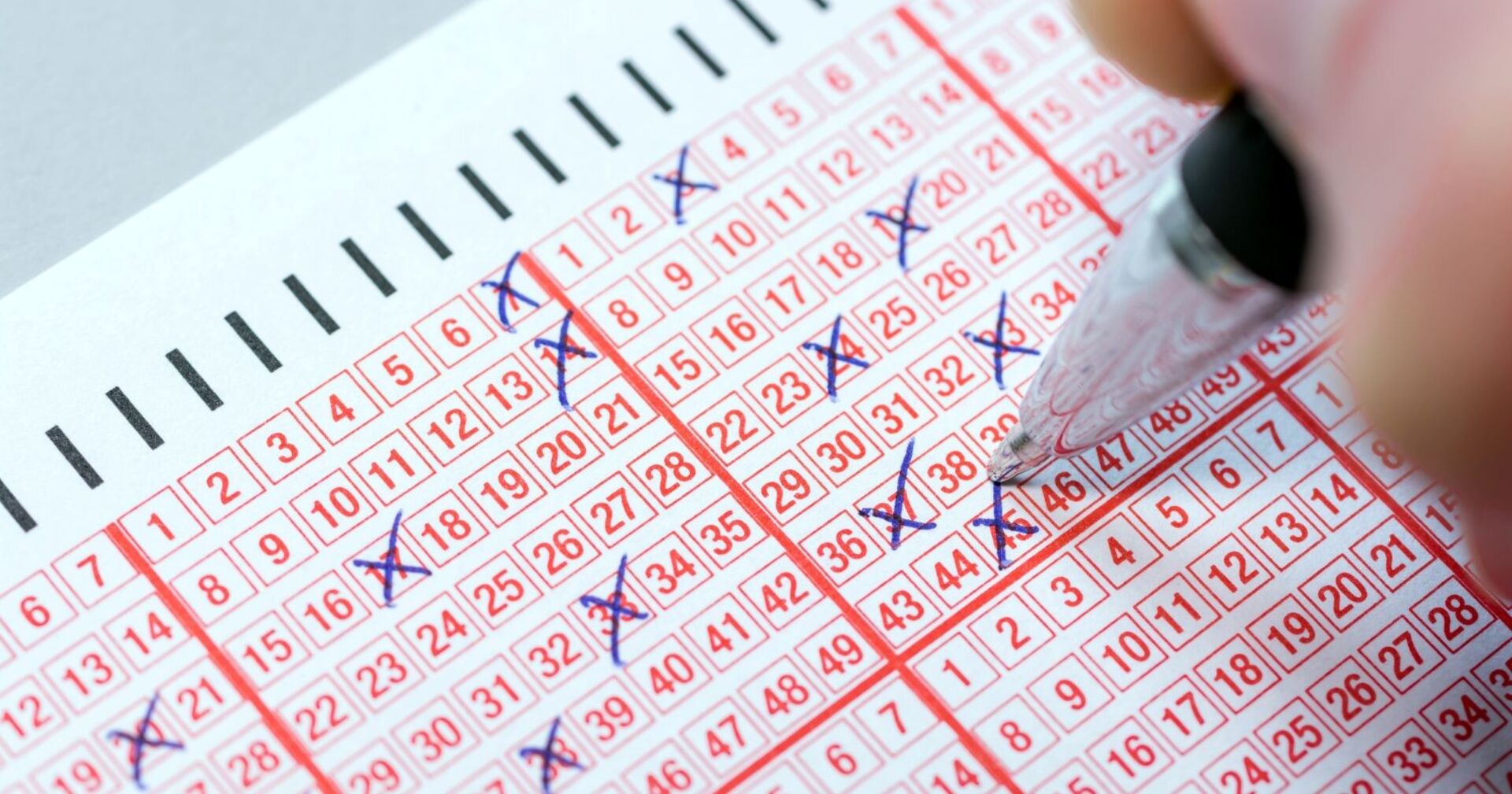 Person kreuzt Zahlen an auf Lottoschein