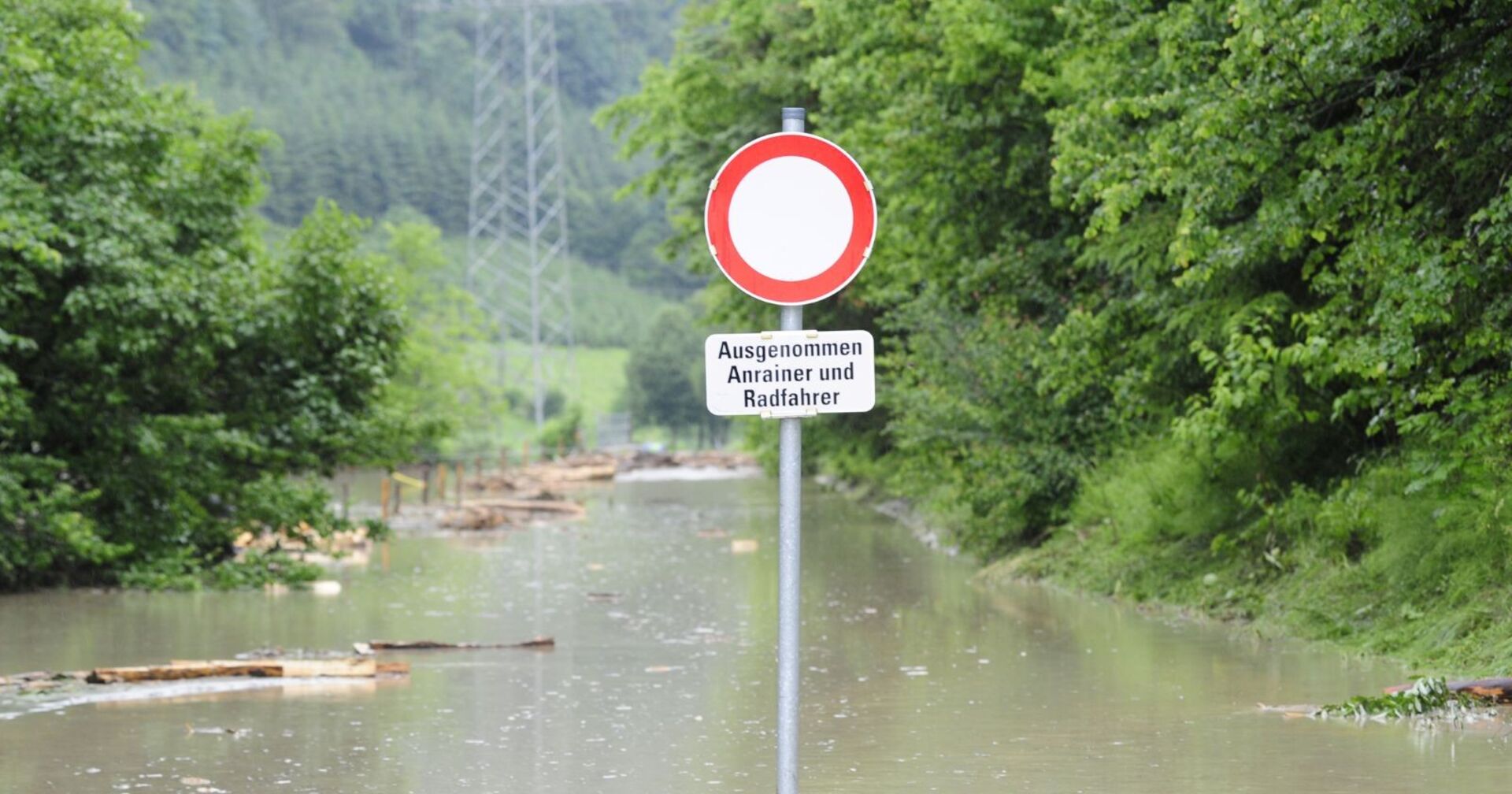 Von Hochwasser betroffene Straße mit einem Fahrverbotsschild, welches herausragt