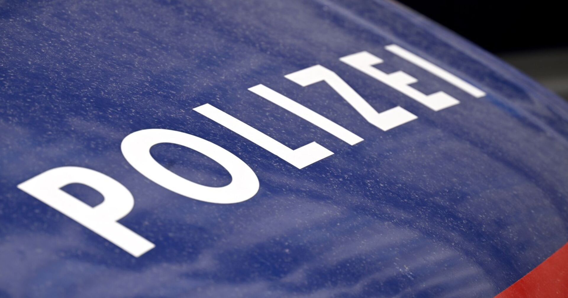 Nahaufnahme eines blauen Polizeifahrzeugs mit weißem Schriftzug „Polizei“.