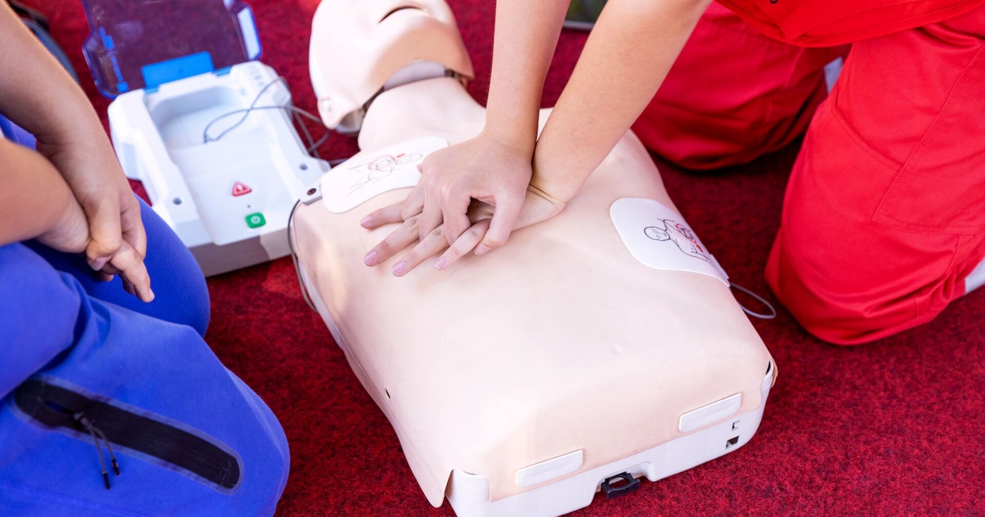Zwei Sanitäter üben an einer Puppe Wiederbelebungsmaßnahmen.