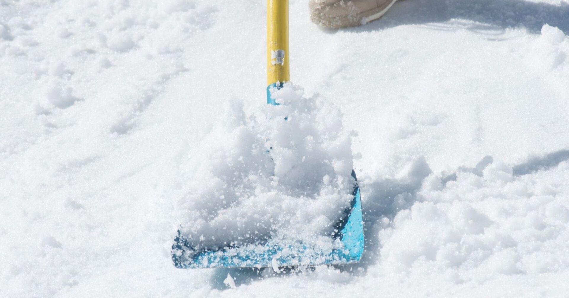 Gelb-blaue Schneeschaufel schaufelt Schnee