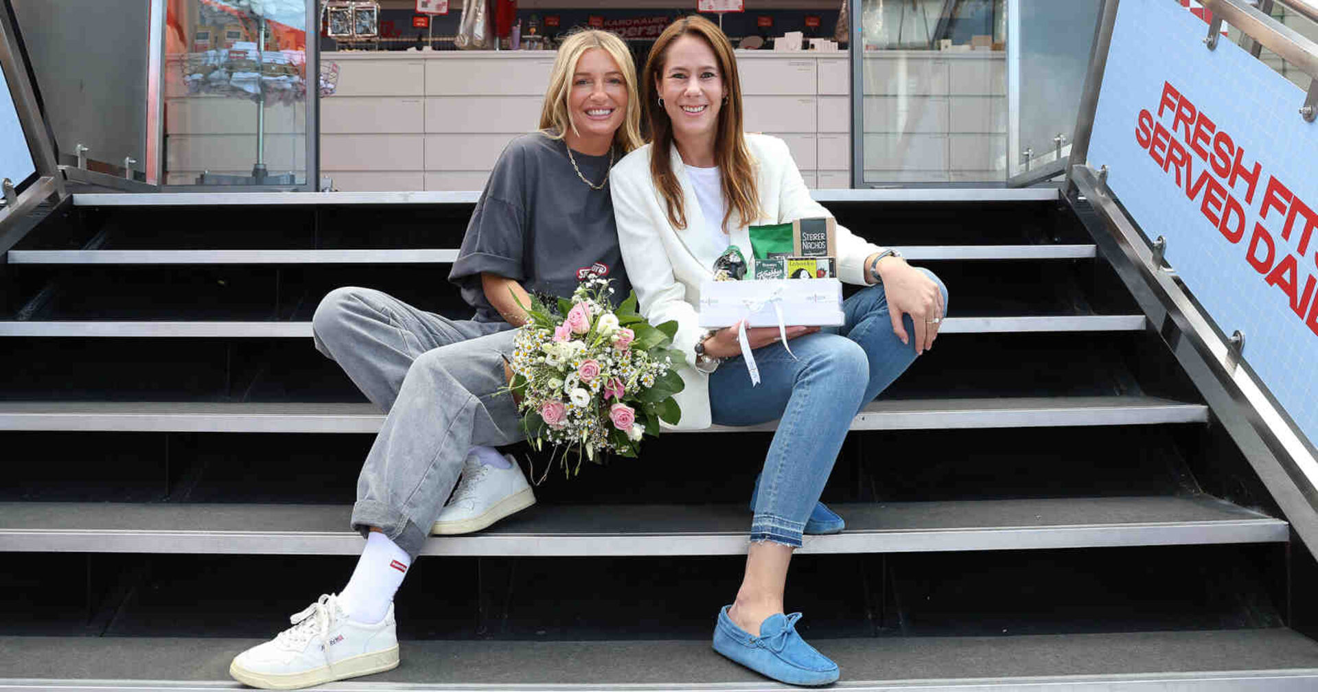 Zwei Frauen sitzen nebeneinander auf einer Treppe