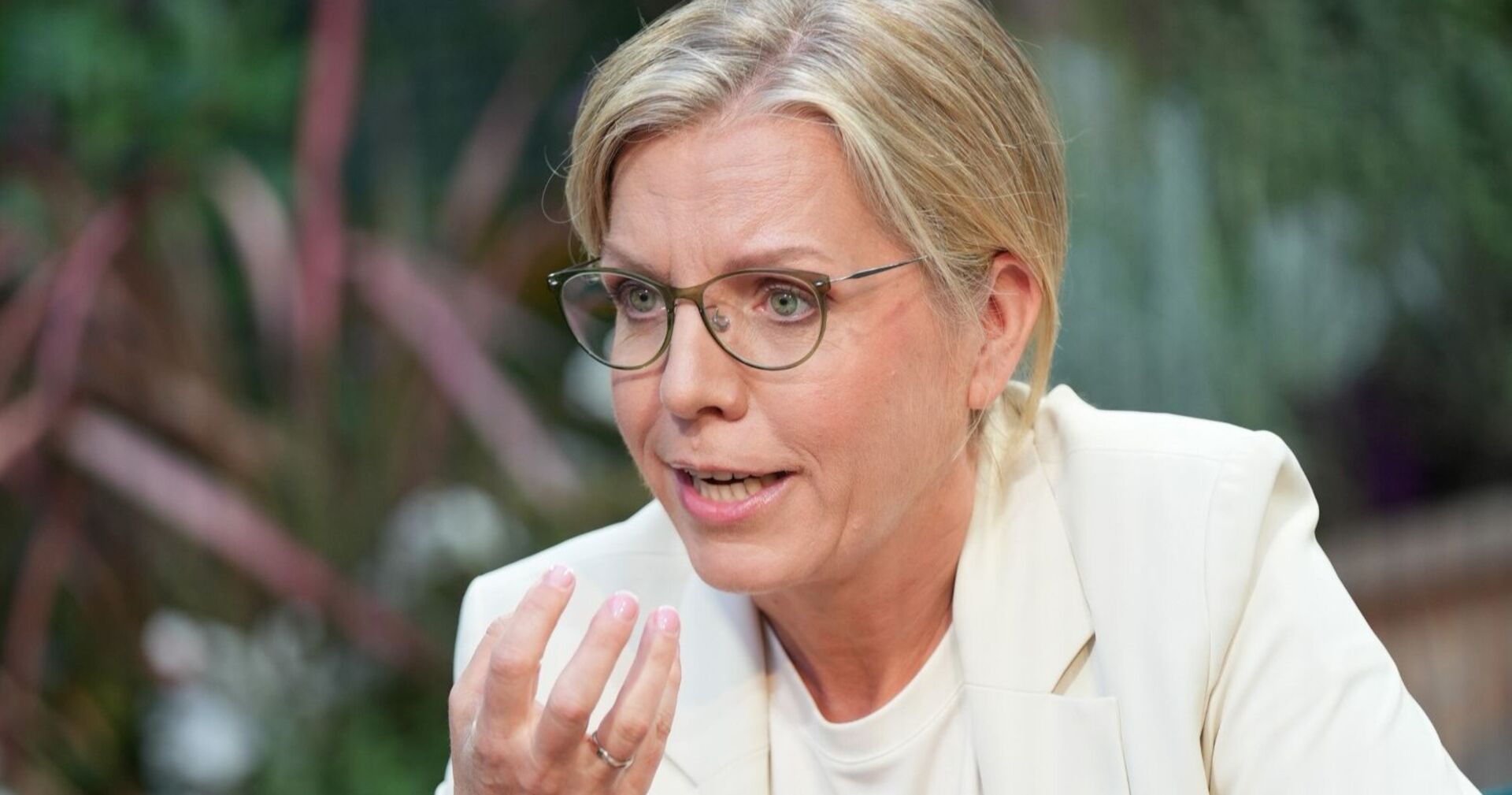 Porträt von Leonore Gewessler beim ORF-Sommergespräch, sie spricht und gestikuliert mit der rechten Hand, trägt eine helle Jacke und Brille.
