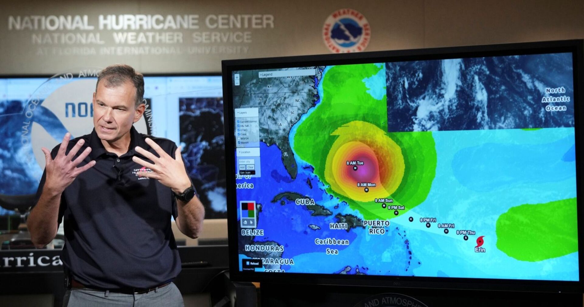 Meteorologe steht vor einer digitalen Wetterkarte mit der prognostizierten Zugbahn von Hurrikan Erin, der sich über der Karibik befindet und in Richtung Südostküste der USA zieht.