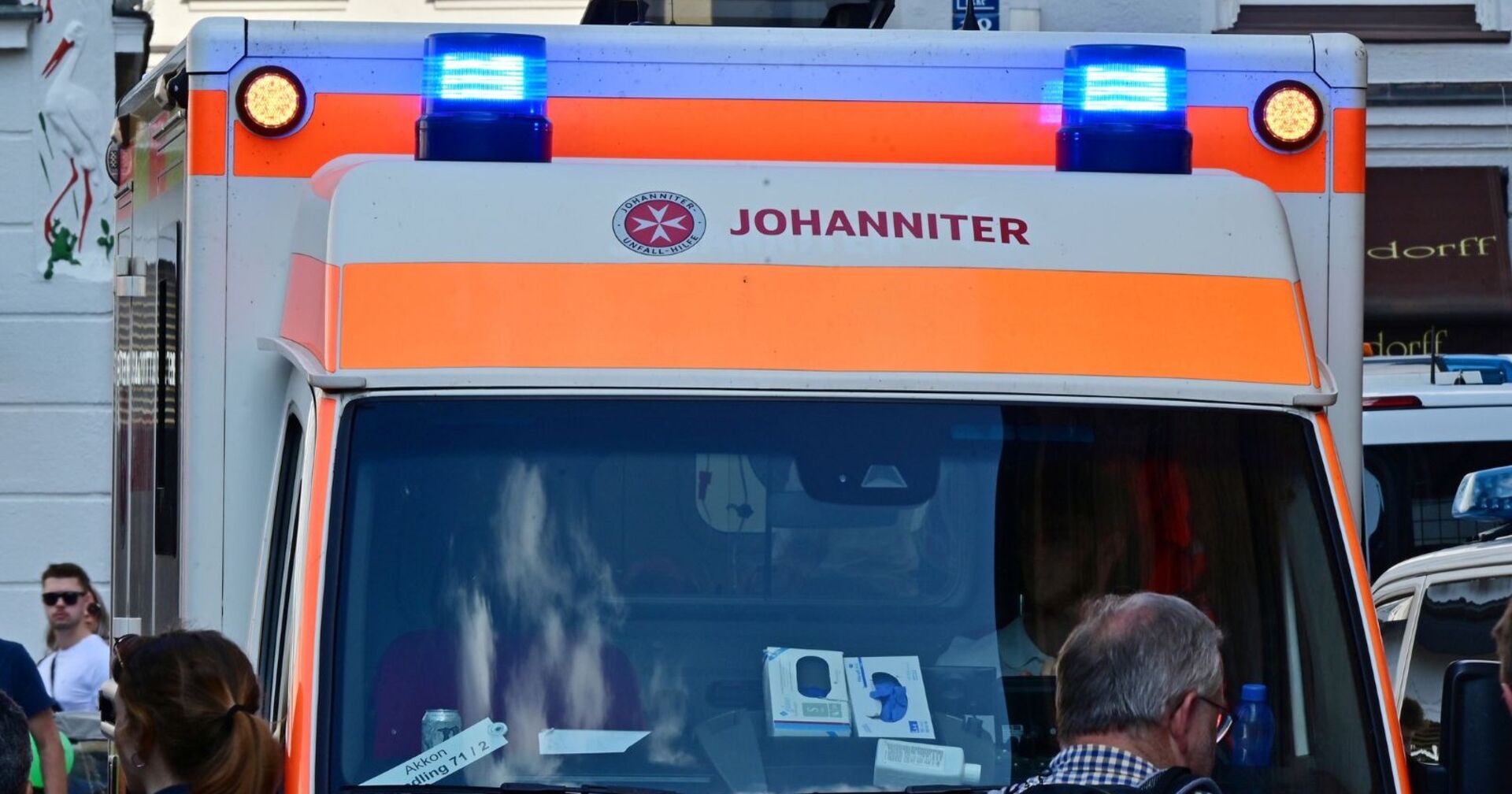 Rettungsfahrzeug der Johanniter mit eingeschaltetem Blaulicht in der Münchner Innenstadt