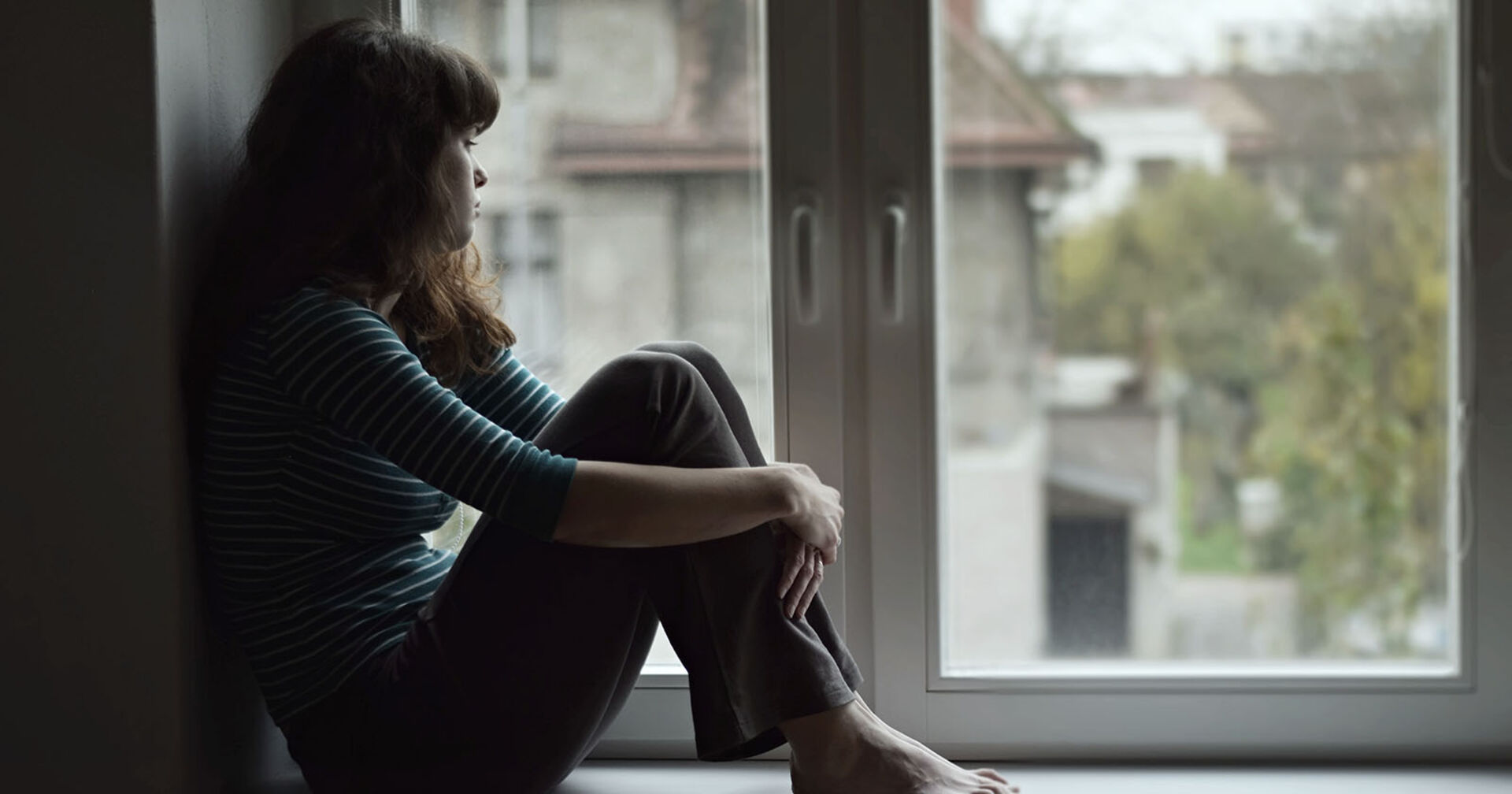 Frau sitzt traurig beim Fenster | Credit: iStock.com/Tunatura