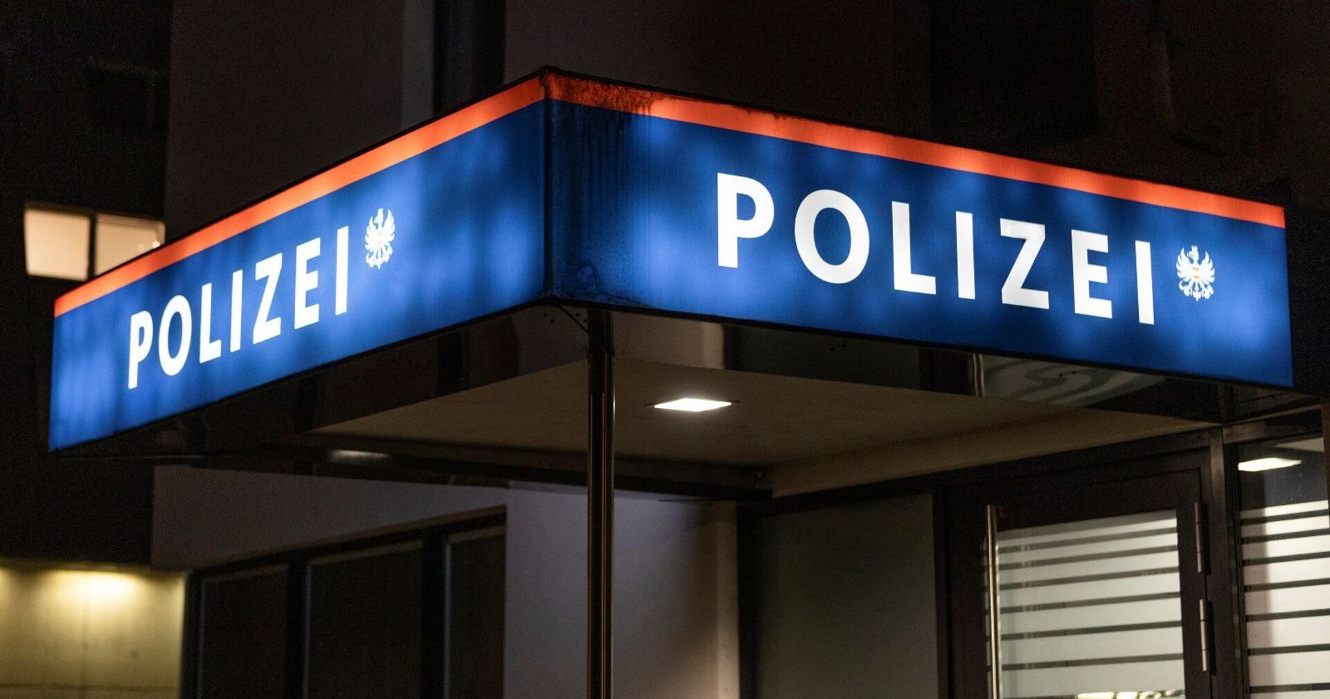 Leuchtendes Schild vor einer Polizeiwache in der Nacht.