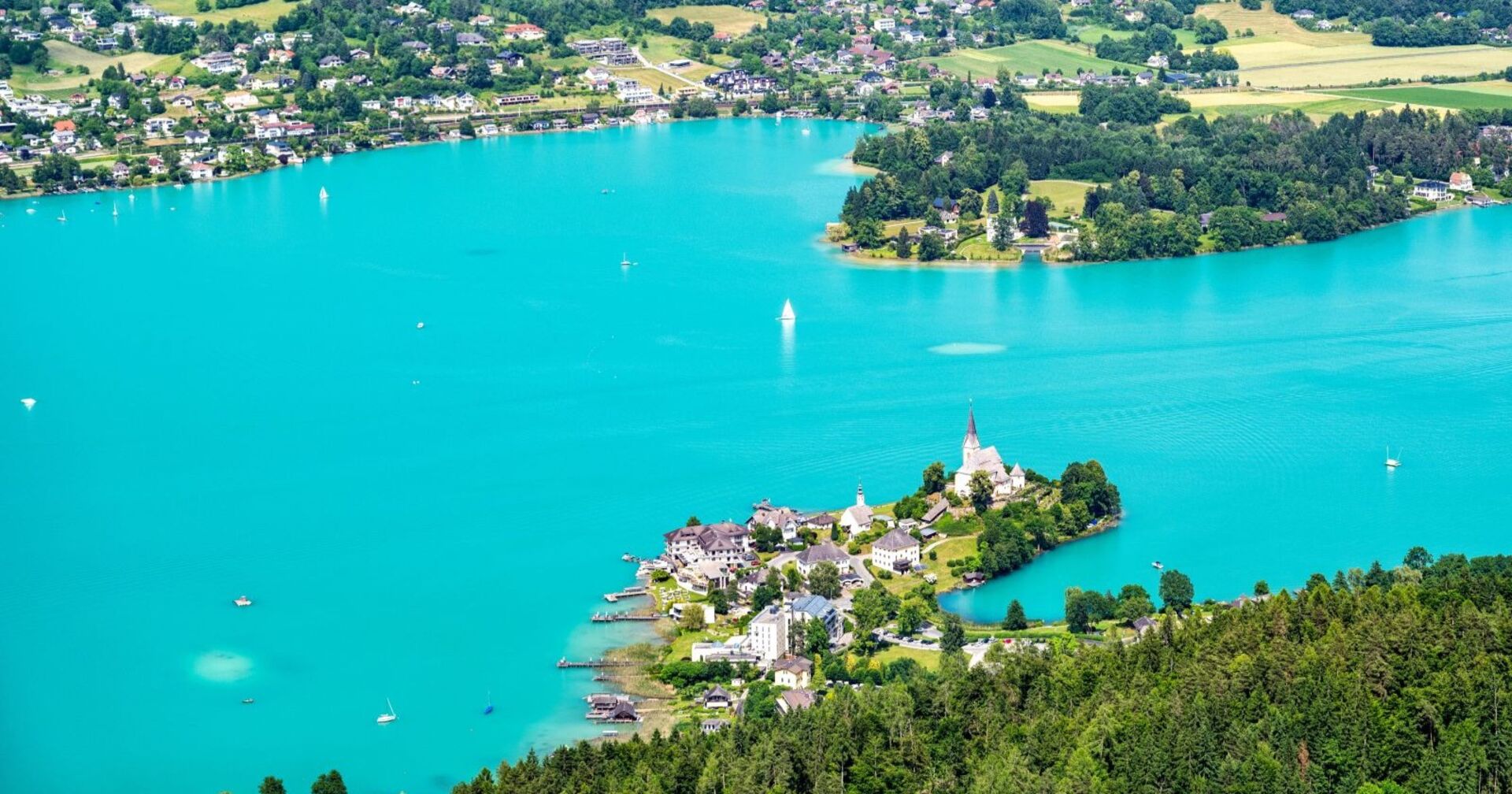 Luftaufnahme von Maria Wörth am Wörthersee mit türkisblauem Wasser, Segelbooten und Uferbebauung, Schauplatz des aktuellen Suchdramas.