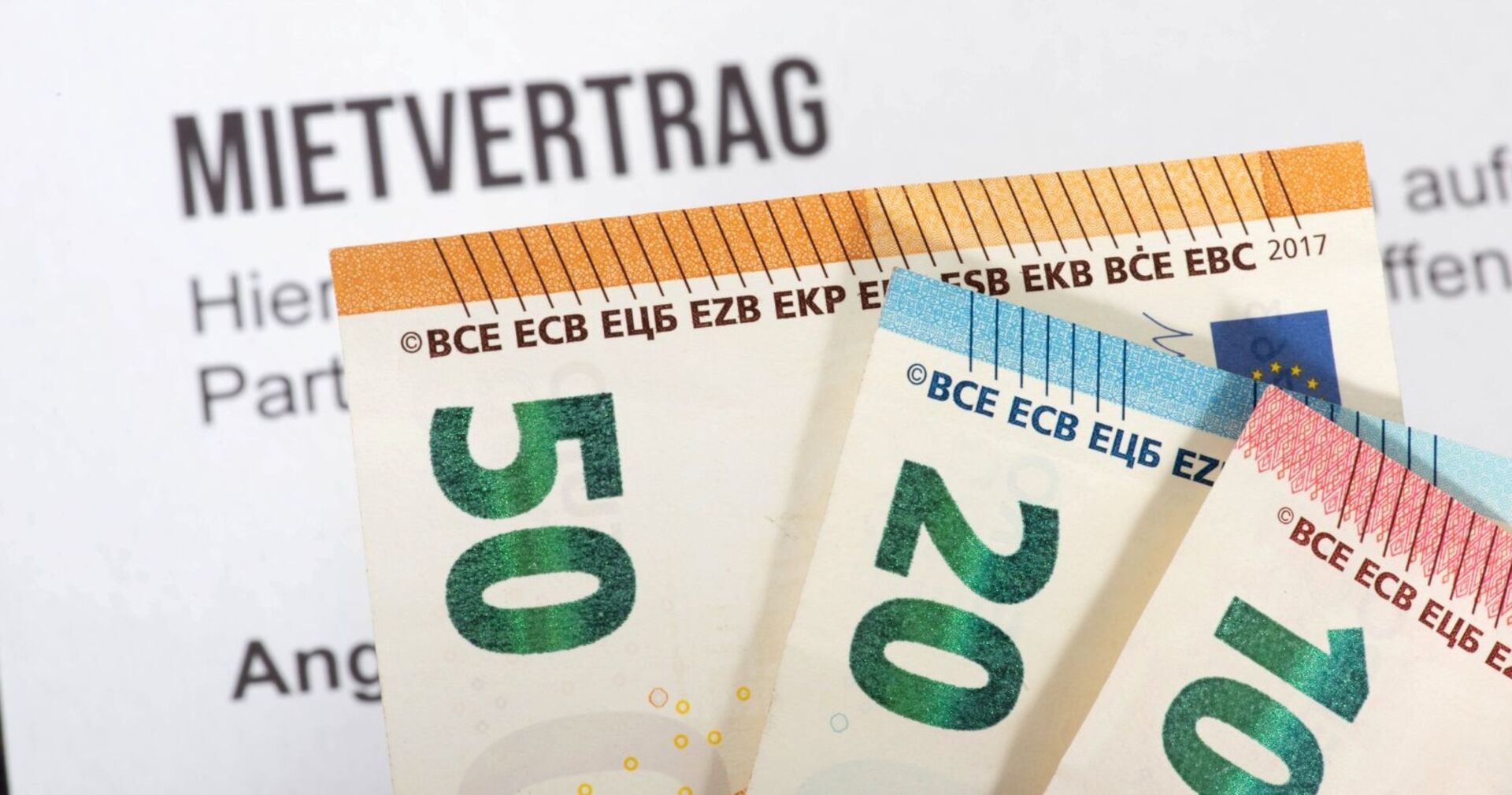 Nahaufnahme von 50-, 20- und 10-Euro-Scheinen, die vor einem Mietvertrag liegen – Symbolbild zum Thema Mietkosten und Vertragsbedingungen.