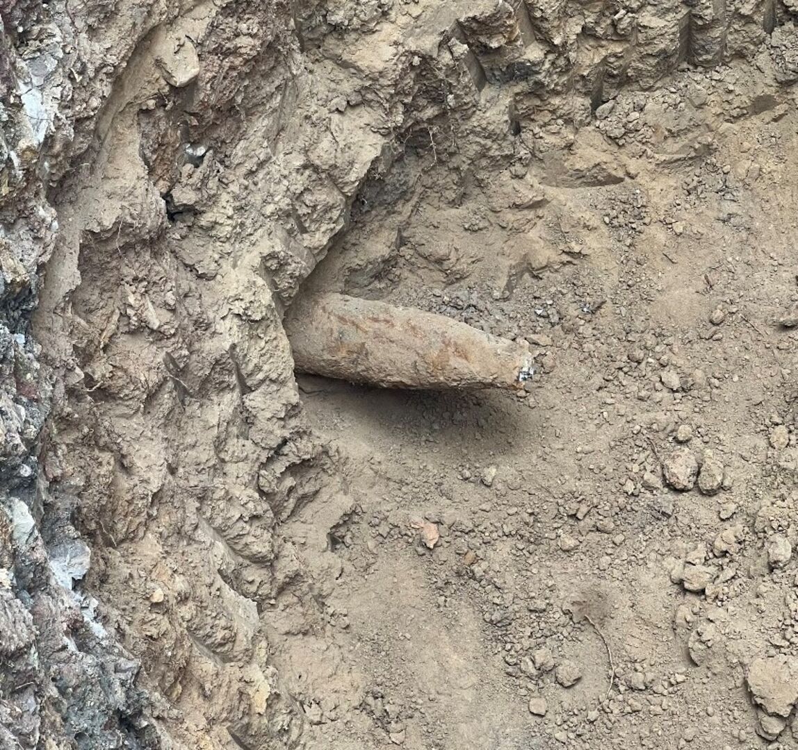 Teilweise freigelegte, rostige mutmaßliche Sprenggranate liegt im Erdreich einer Baugrube in Wien-Penzing.        ChatGPT fragen