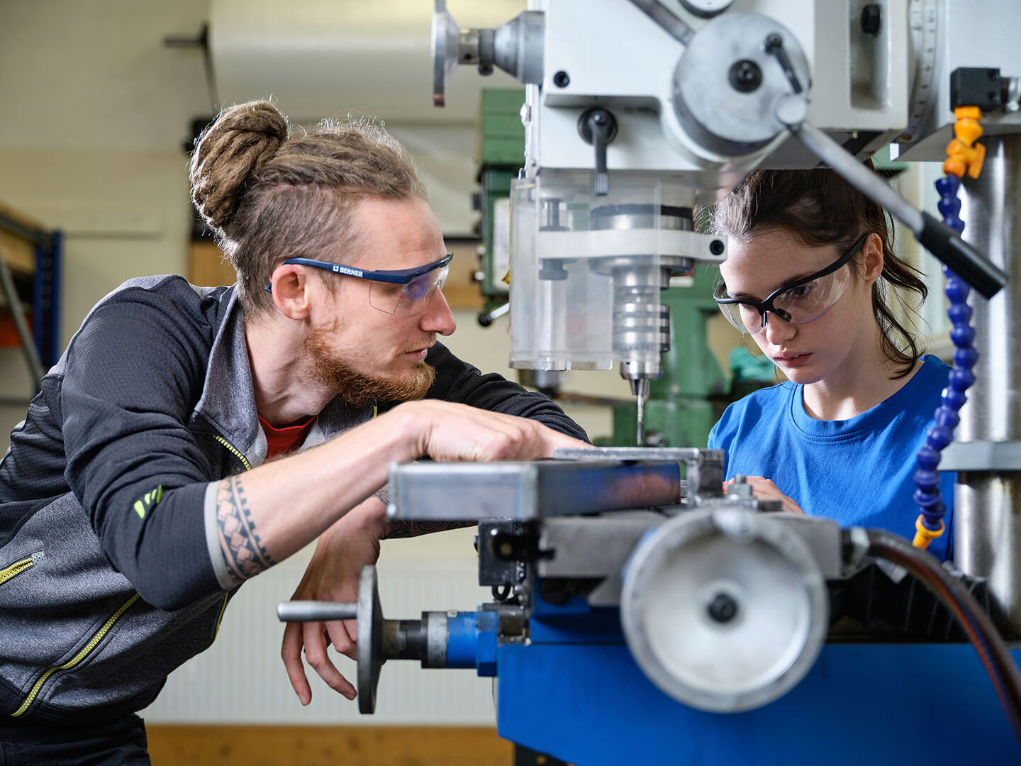 Männlicher und weiblicher Lehrling mit Schutzbrillen bei der Arbeit an der Werkbank | Credit: Fokus Mensch