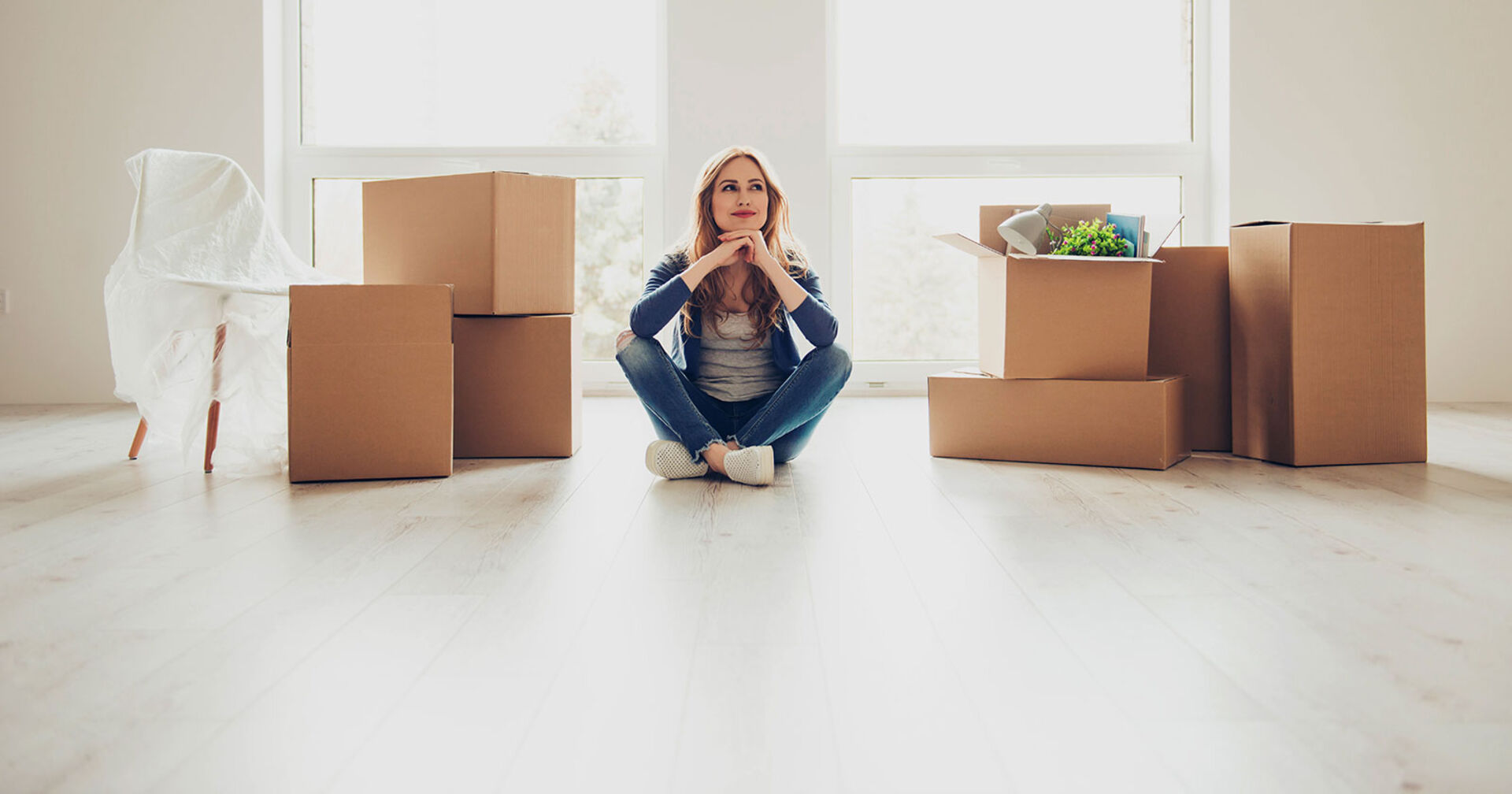 Frau vor Umzugkartons in ihrer leeren Wohnung | Credit: iStock.com/Deagreez