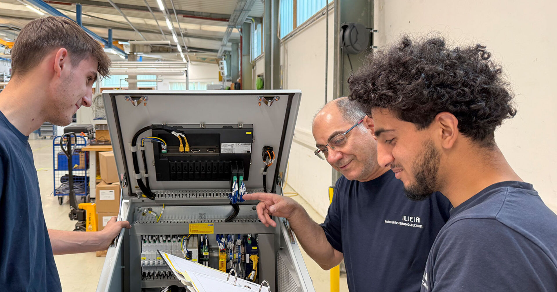Ausbildner in der Werkshalle mit Lehrlingen im Gespräch | Credit: Lea Automatisierungstechnik