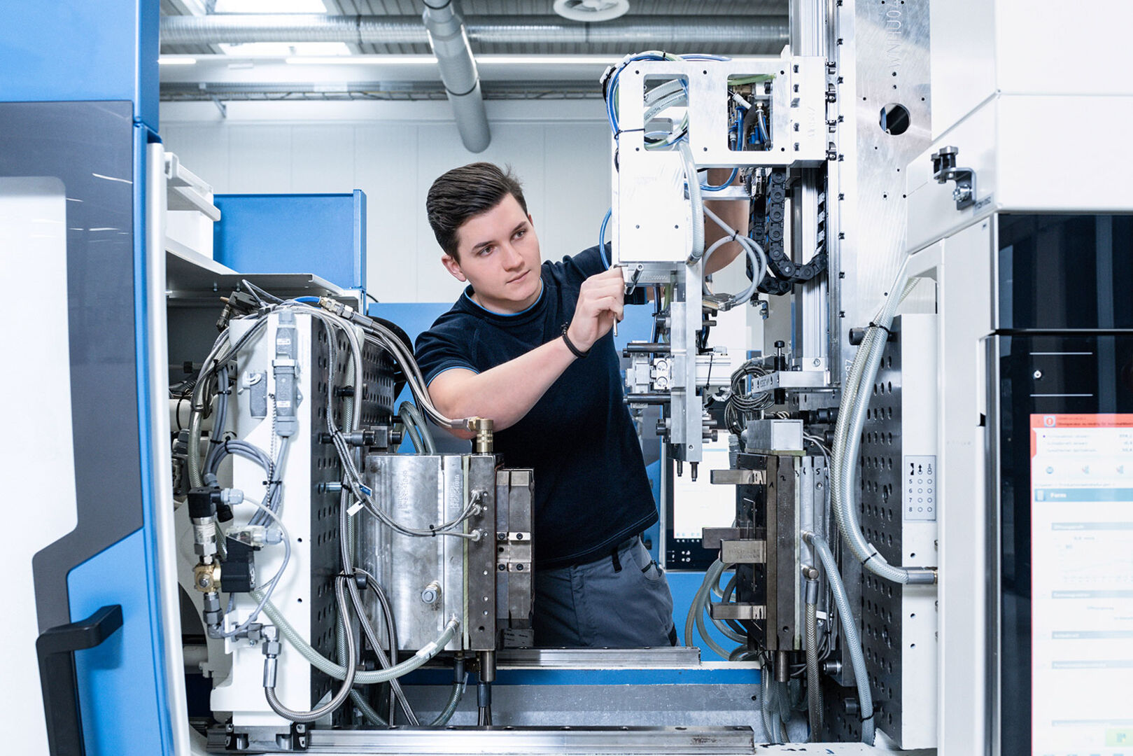 Männlicher Lehrling bei der Montage in einer Werkshalle | Credit: STARLIM Spritzguss