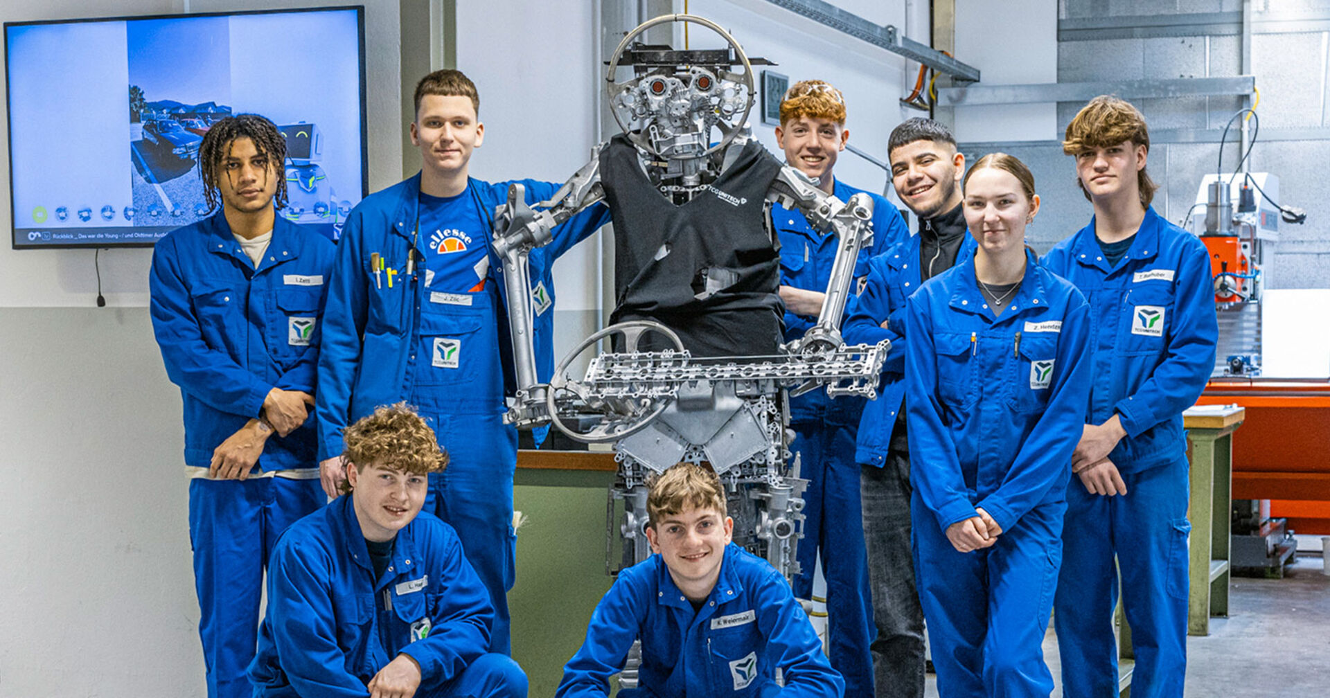 Gruppe von Lehrlingen in blauer Arbeitskleidung posiert für ein Foto | Credit: TCG UNITECH