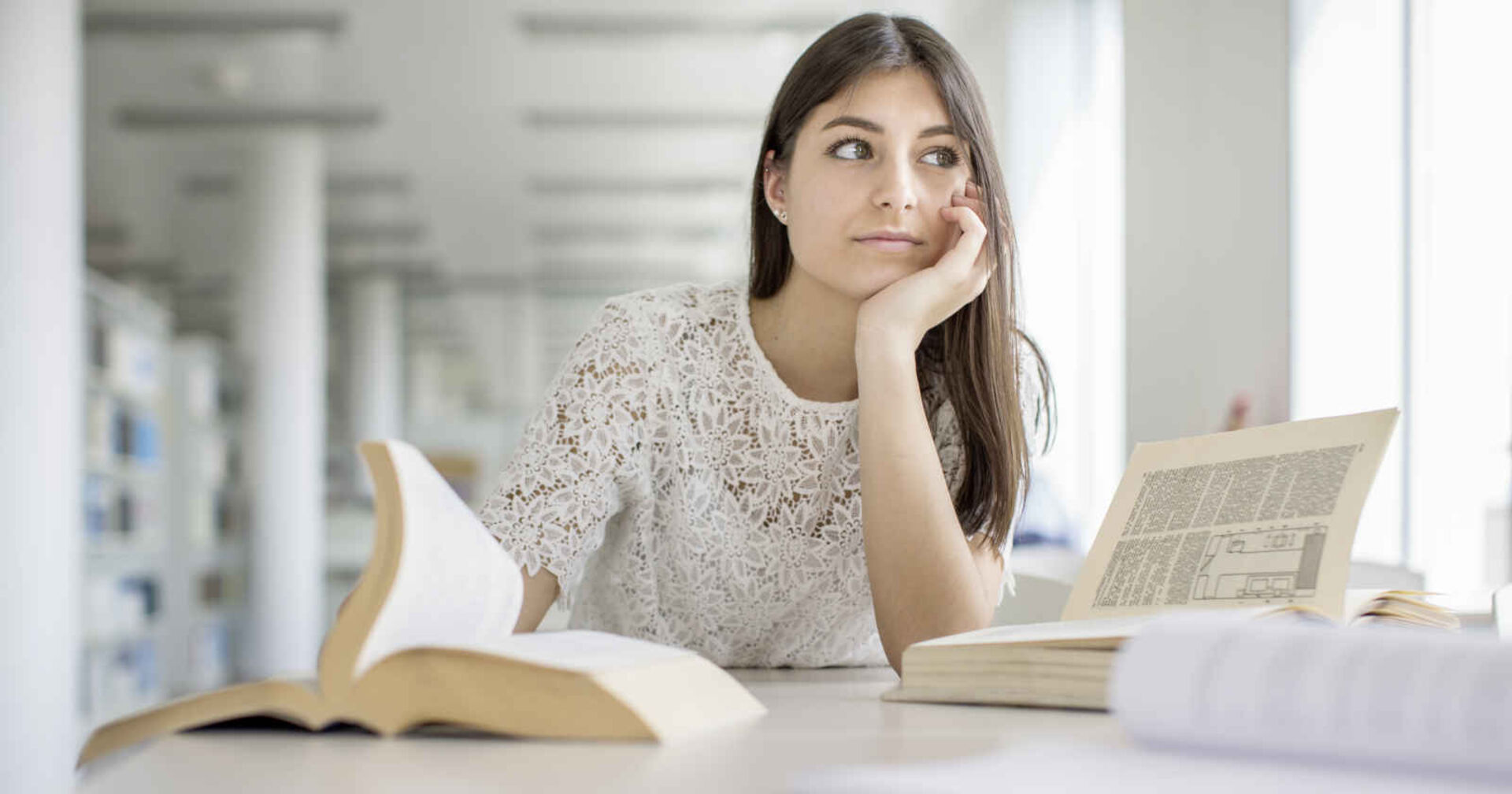 Nachdenkliches Mädchen sitzend vor einem Schreibtisch